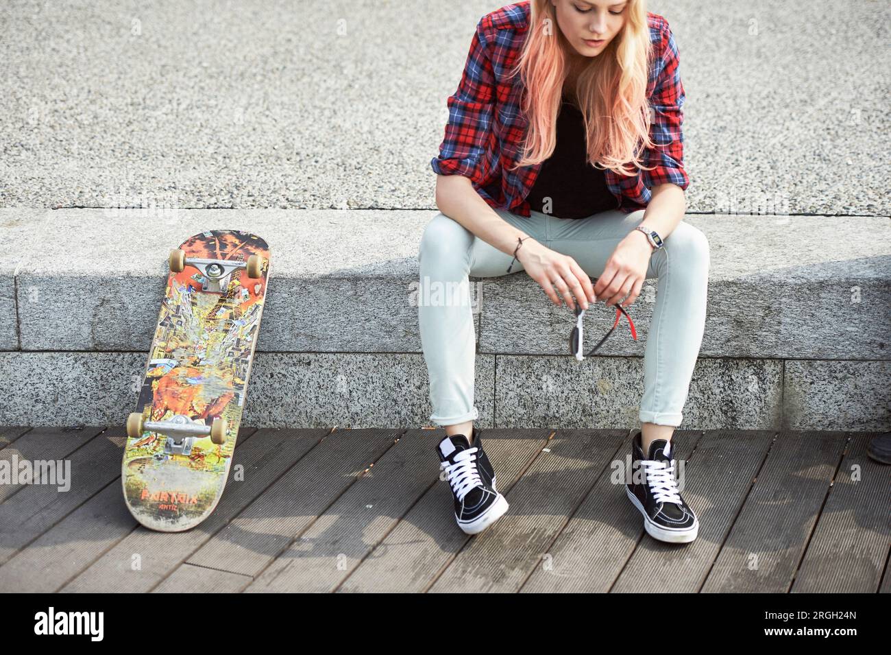 Junges Mädchen sitzt von Skateboard Stockfoto