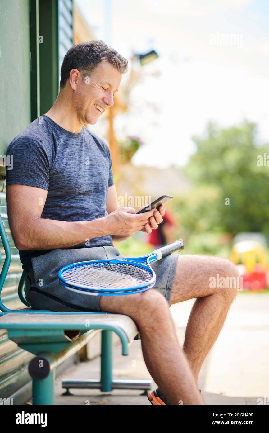 Reifen Mann mit Tennisschläger und Smart Phone Stockfoto