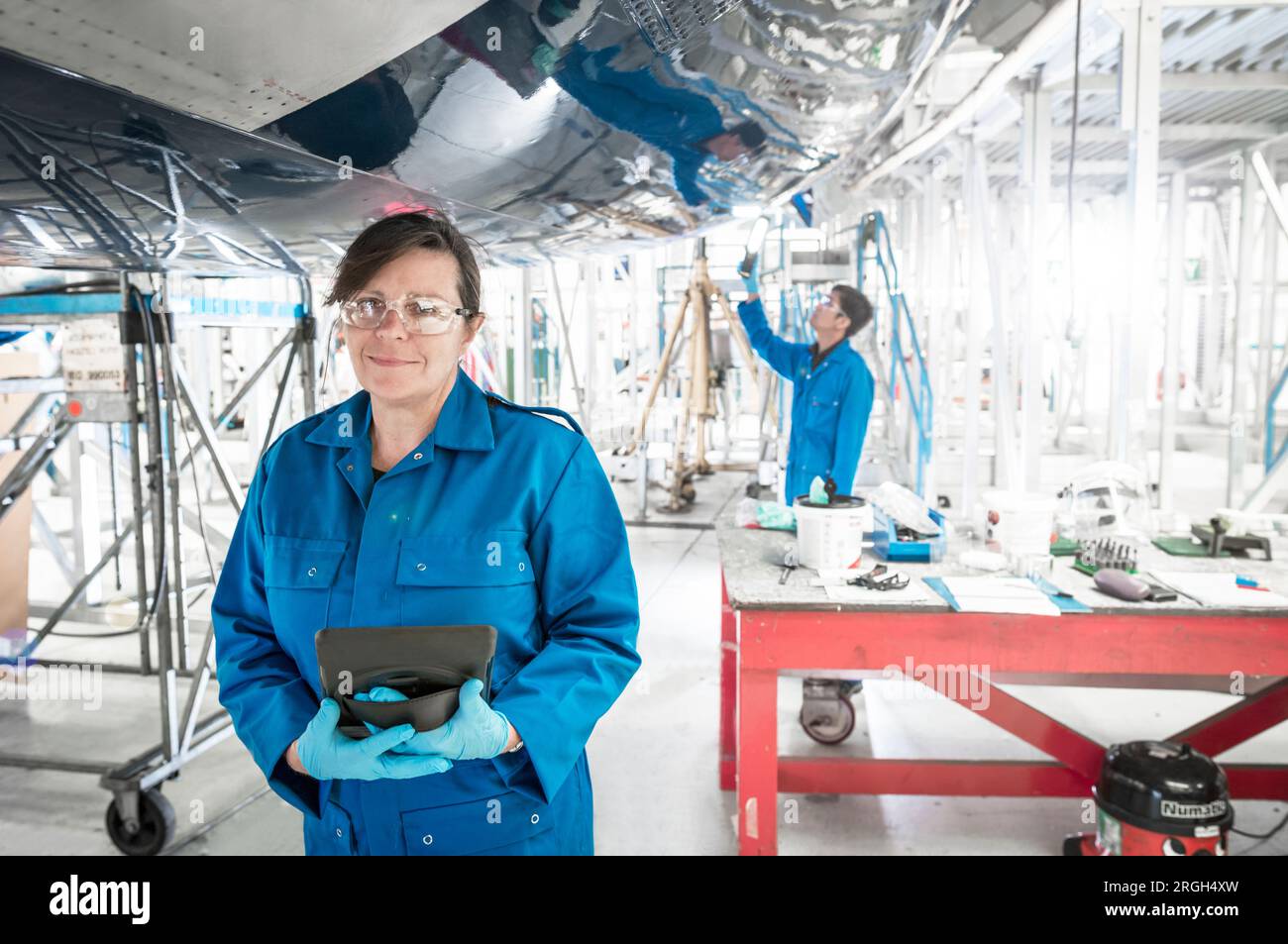 Frau, die ein digitales Tablet im Flugzeug im Hangar hält Stockfoto