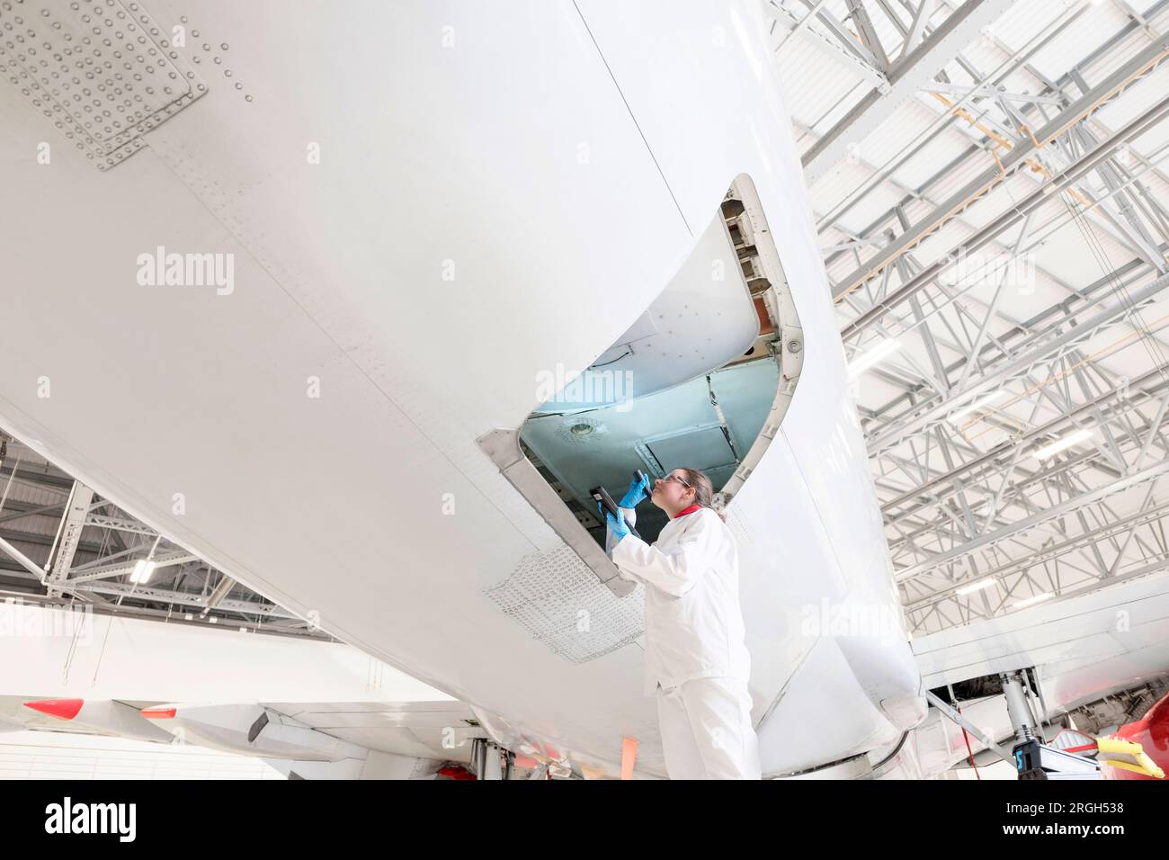 Arbeiterin mit Taschenlampe im Flugzeugeingang Stockfoto