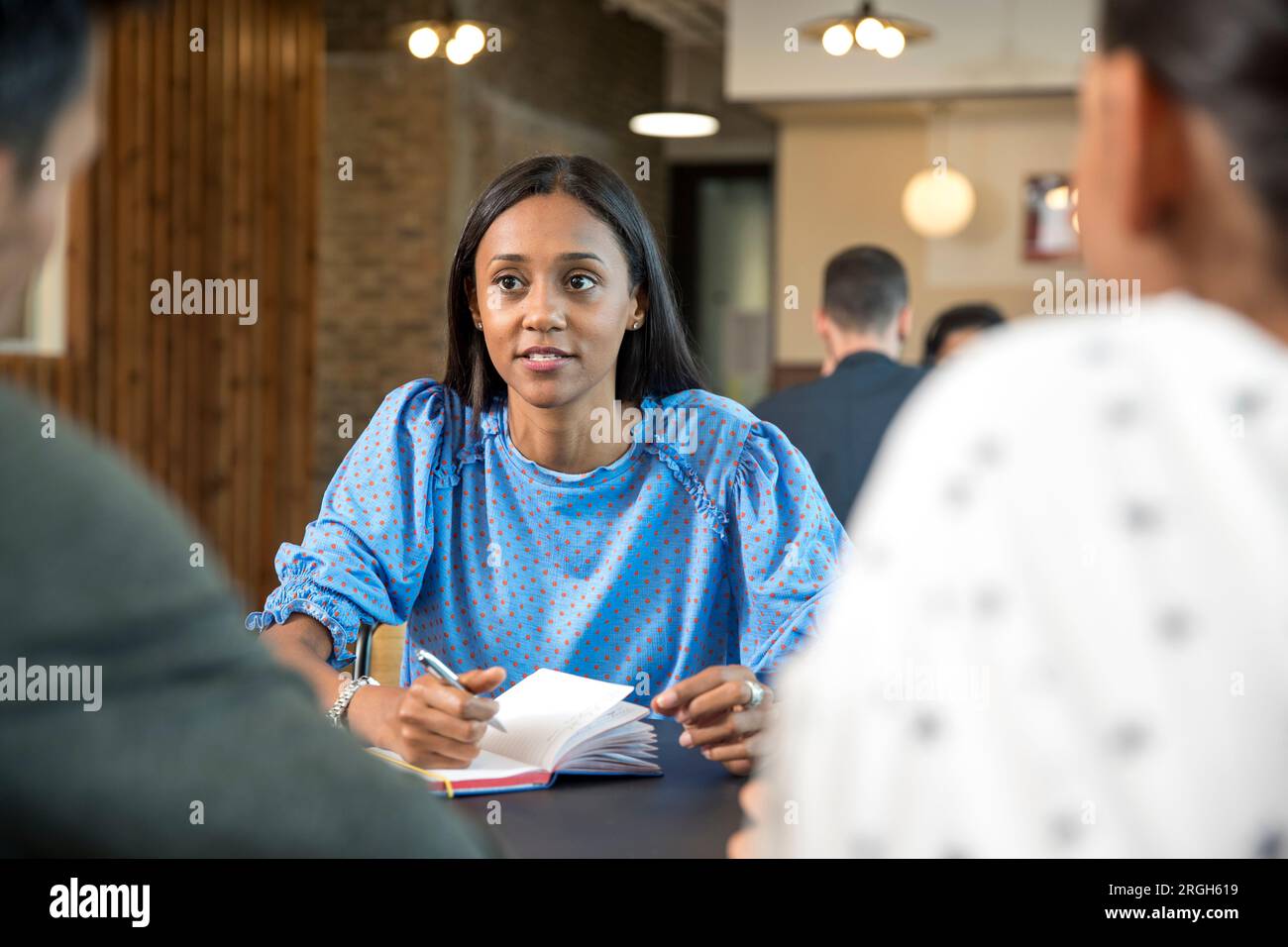 Mitte der erwachsenen Frau mit Notebook während Konferenz Stockfoto