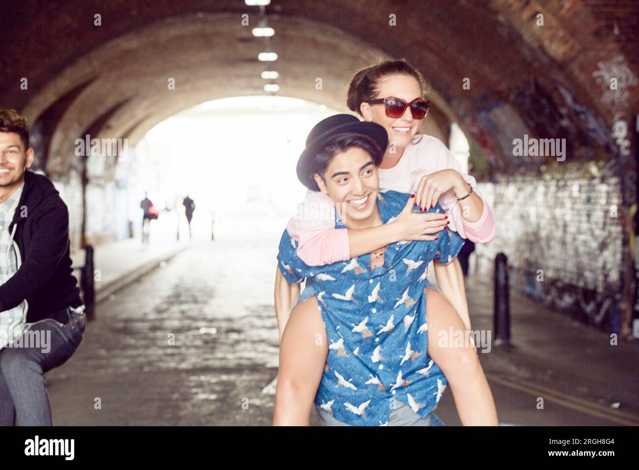 Teenager, die Freundin piggyback Ride im Tunnel Stockfoto