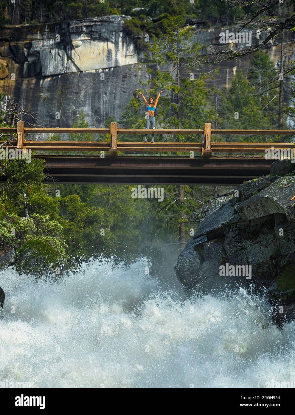 Junge Frau, die ihre Arme Anheben auf einer Brücke Stockfoto