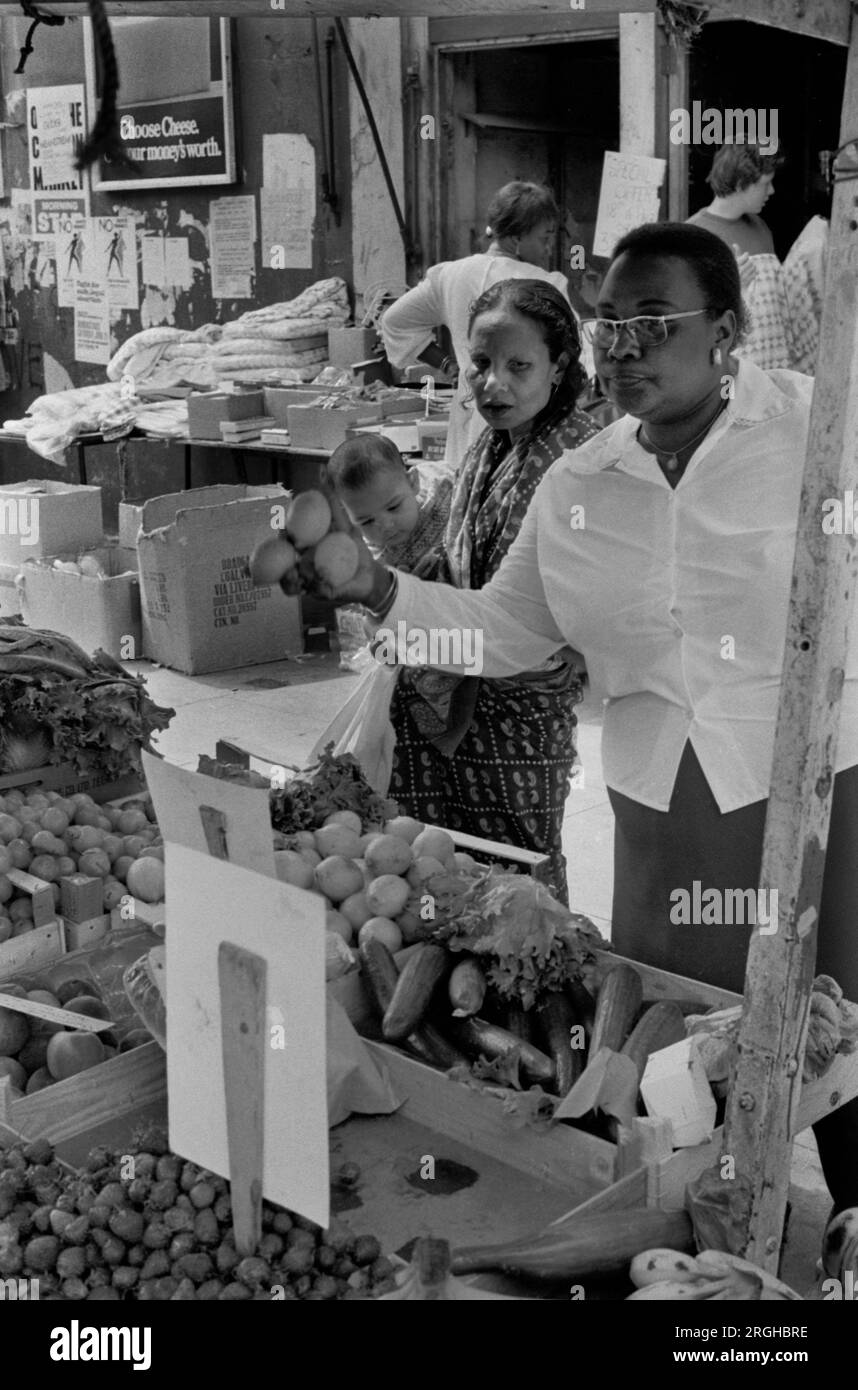 Portobello Road Notting Hill London 1970er. Samstag Marktstand. Schwarze und asiatische britische Frauen kaufen Obst 1975, multiethnisches Großbritannien 1970er UK HOMER SYKES Stockfoto