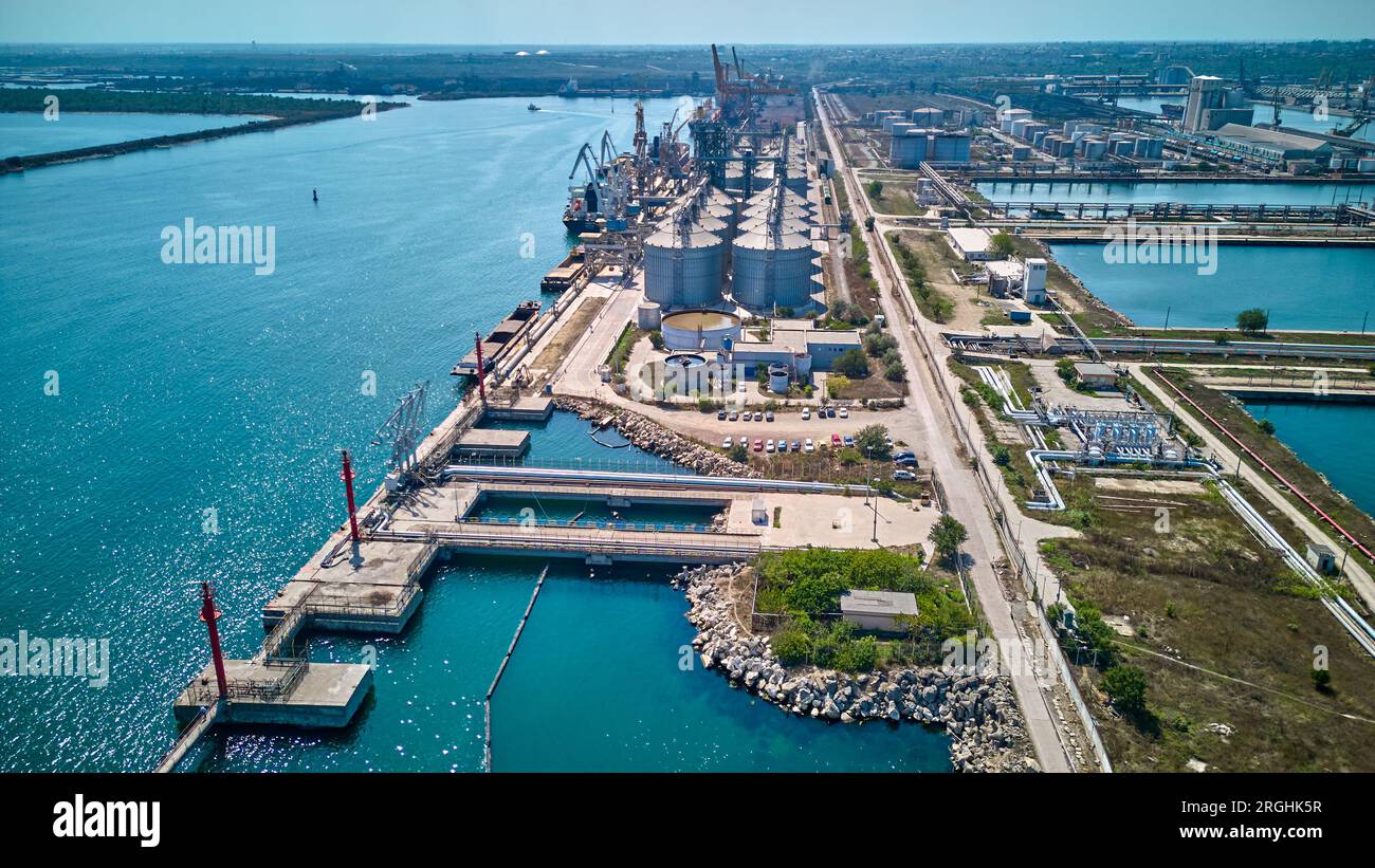 Verladung von Getreide in Laderäume von Seefrachtschiffen aus Getreidesilos im Seehafen. Bunkerung von Trockenfrachtschiffen mit Getreide. Draufsicht. Stockfoto