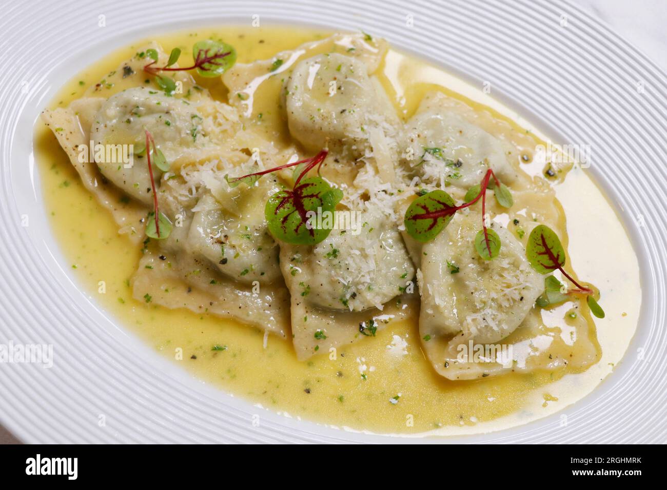 Italienische Küche, mit Pilzen gefüllte Ravioli-Pasta mit cremiger Parmesan-Käsesauce auf einem weißen Teller Stockfoto