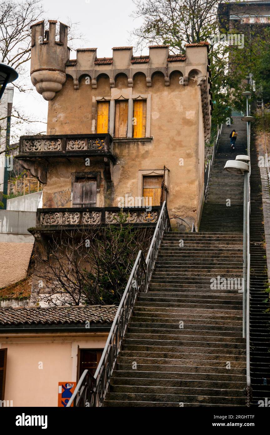 Zinnen, ein Turm und Dreifachfenster neben einer langen Treppe und stillgelegte Standseilbahn im italienischsprachigen Lugano, Schweiz. Stockfoto