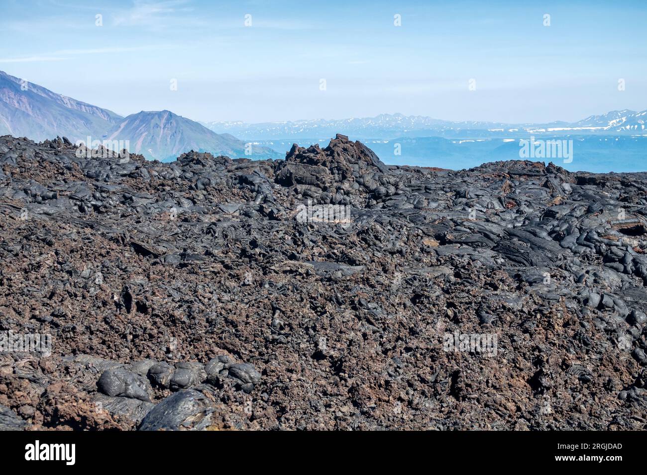 Ausgedehnte Basaltfelder (Trappide) Lava mit fragmentierten Skorien (Trappide) gegen Vulkane und Berge. Sphäulitische Lava. Kamtschatka, Russland Stockfoto