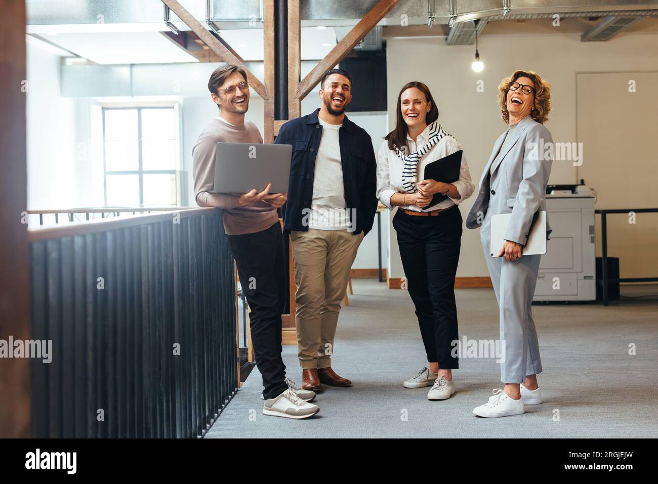 Erfolgreiches Business-Team, das lacht, während es zusammensteht. Eine Gruppe von Technikexperten bereitet sich auf ein Standdup-Meeting in einem Büro vor. Stockfoto