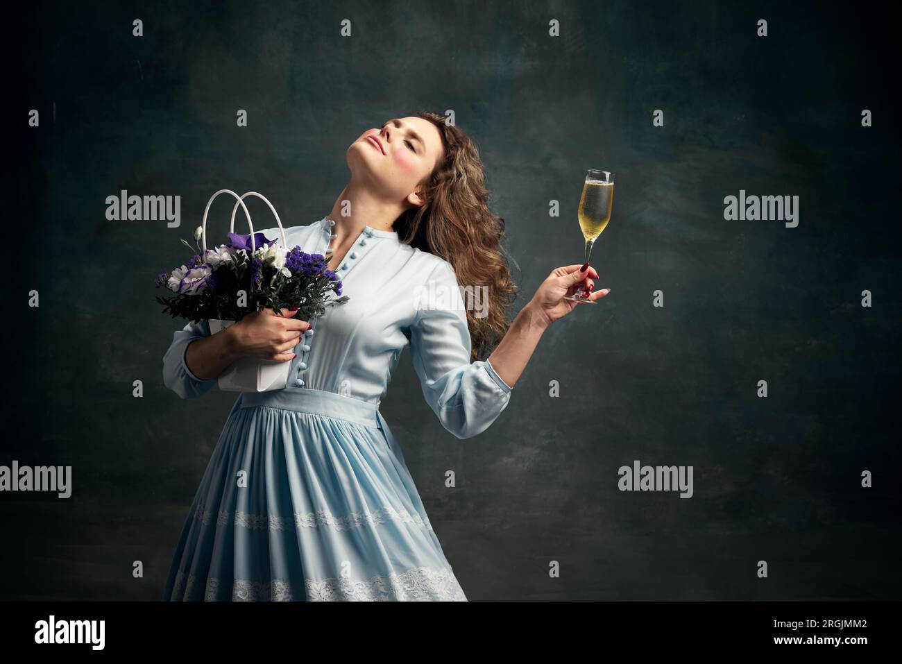 Königin. Träumende aristokratische, entspannende Frau in blauem historischen Kleid und Tanz mit einem Glas Schampfer und einem Blumenstrauß. Stockfoto