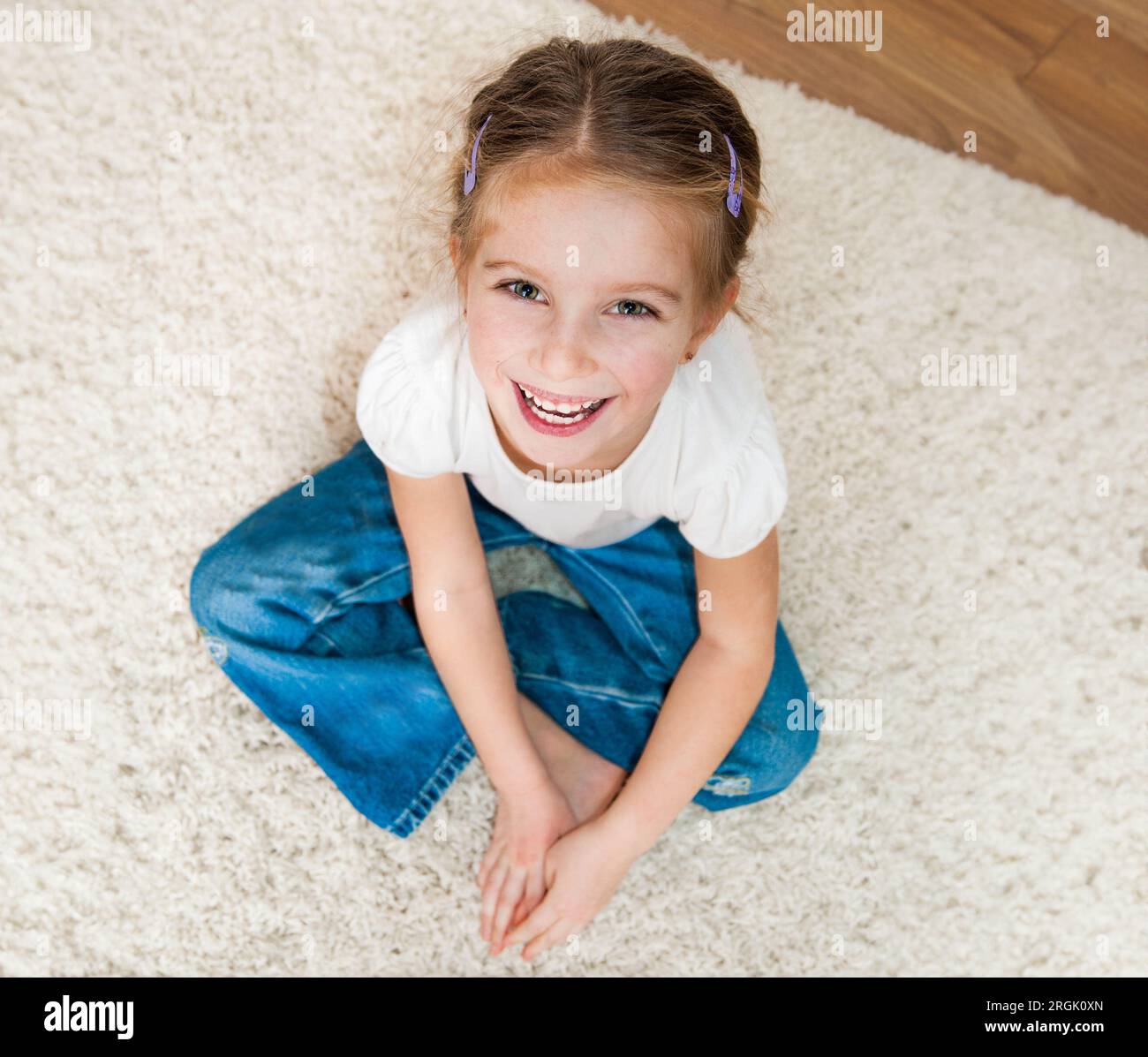 Süßes kleines Mädchen, das auf dem Boden sitzt Stockfoto