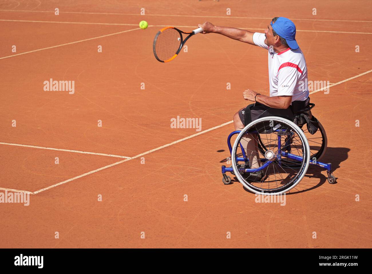 Ein Mann übt Tennis im Rollstuhl auf einem Tonplatz. Rollstuhltennis. Stockfoto