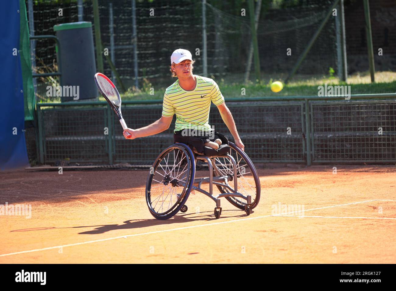 Ein Mann übt Tennis im Rollstuhl auf einem Tonplatz. Rollstuhltennis. Stockfoto