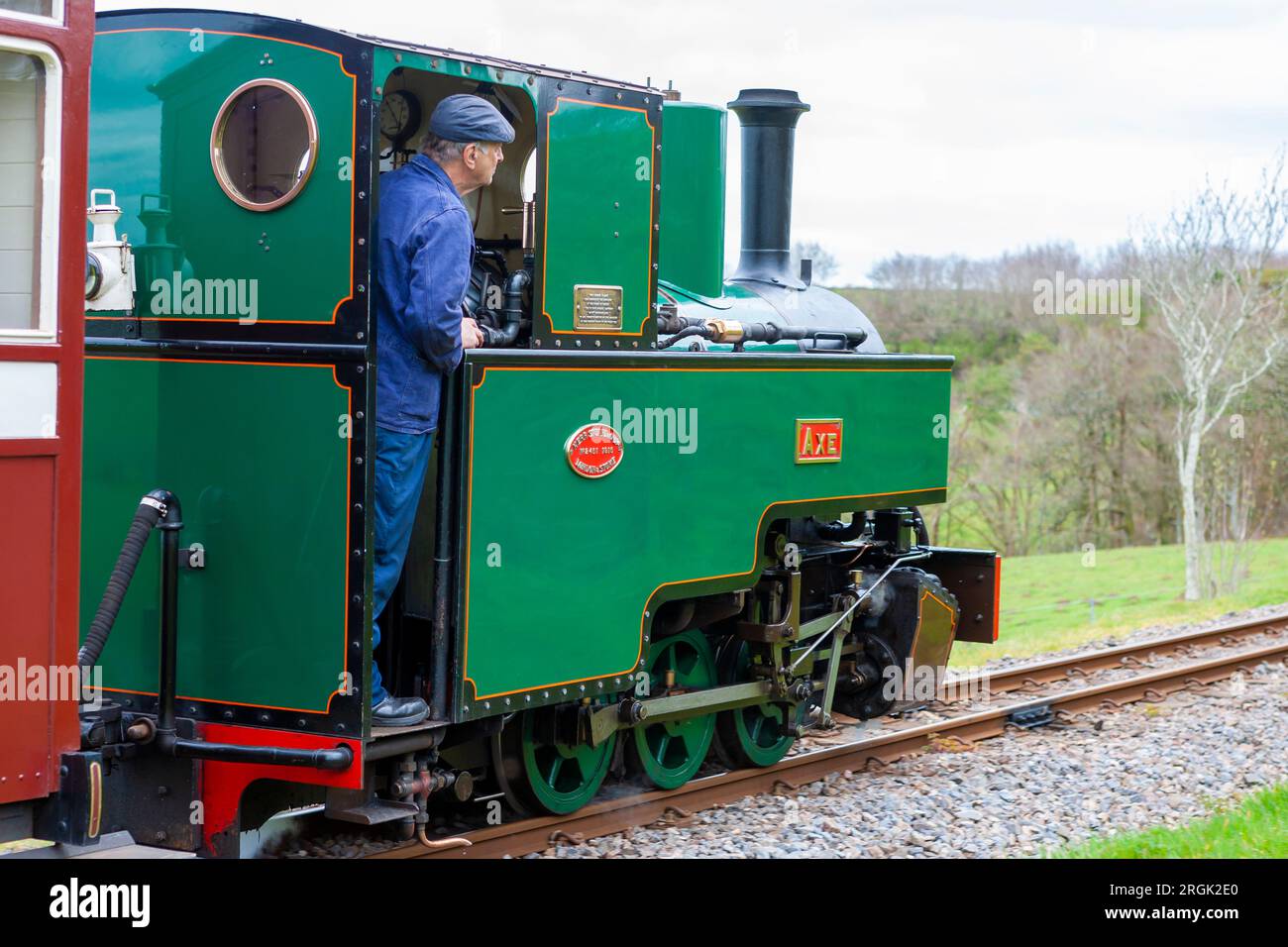Fahrer auf der Fußplatte der Joffre Class 'Axe' Lokomotive, die einen Zug zum Bahnhof Woody Bay auf der Lynton und Barnstaple Railway, Devon, Großbritannien, fährt Stockfoto