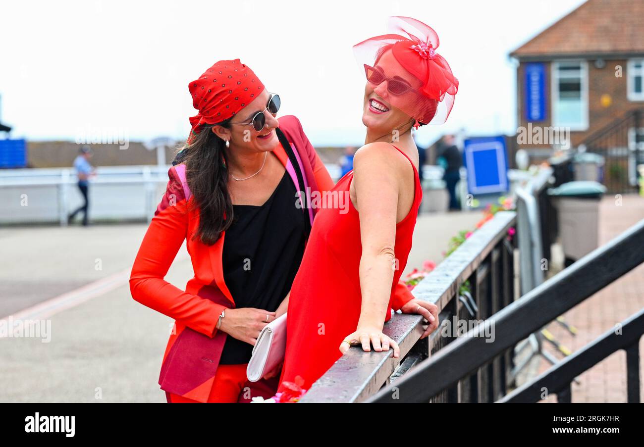Brighton UK 10. August 2023 - Dimana Popovska (links) und Grace Thornton in Rot, während sie das heiße sonnige Wetter am Brighton Races Ladies Day während ihres Star Sports 3 Day Festival of Racing genießen: Credit Simon Dack / Alamy Live News Stockfoto