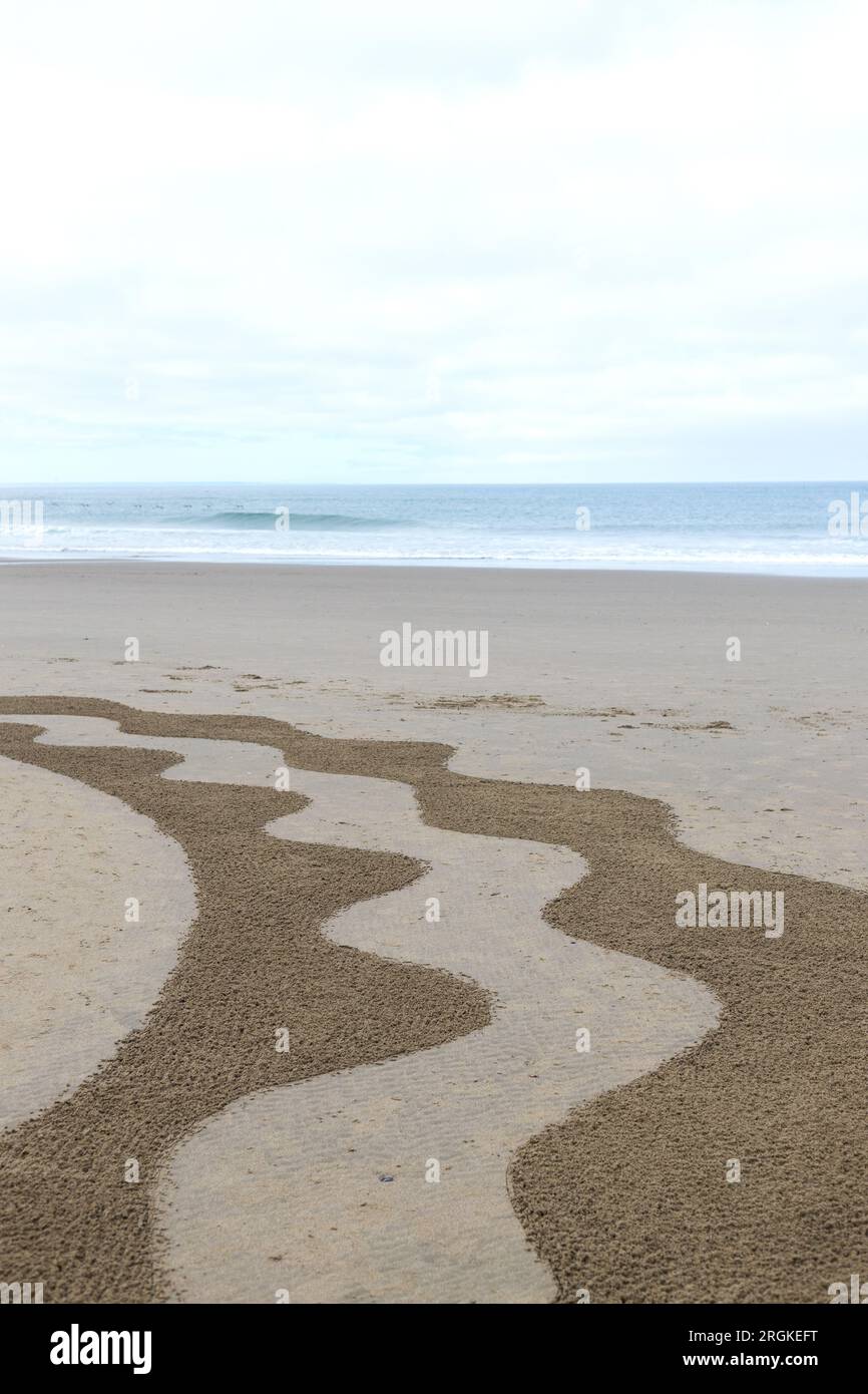 Ein Abschnitt eines Sandlabyrinths an einem Strand mit Meer und Himmel im Hintergrund. Stockfoto