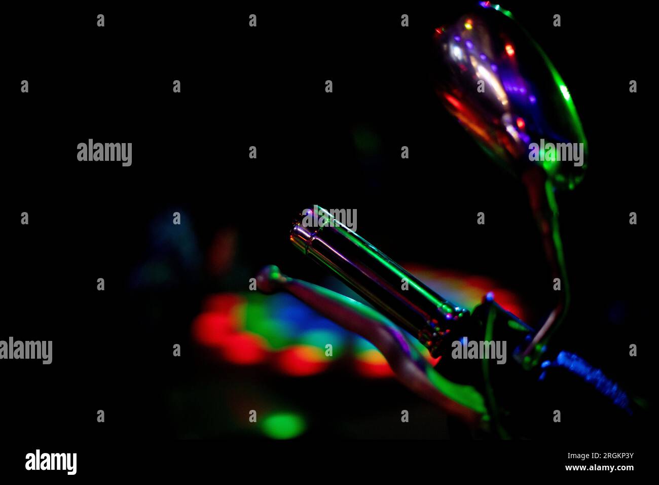 Motorraddetails im farbigen Licht. Transport in der Disco. Licht auf Objekt. Rückspiegel und Motorradgriff. Stockfoto