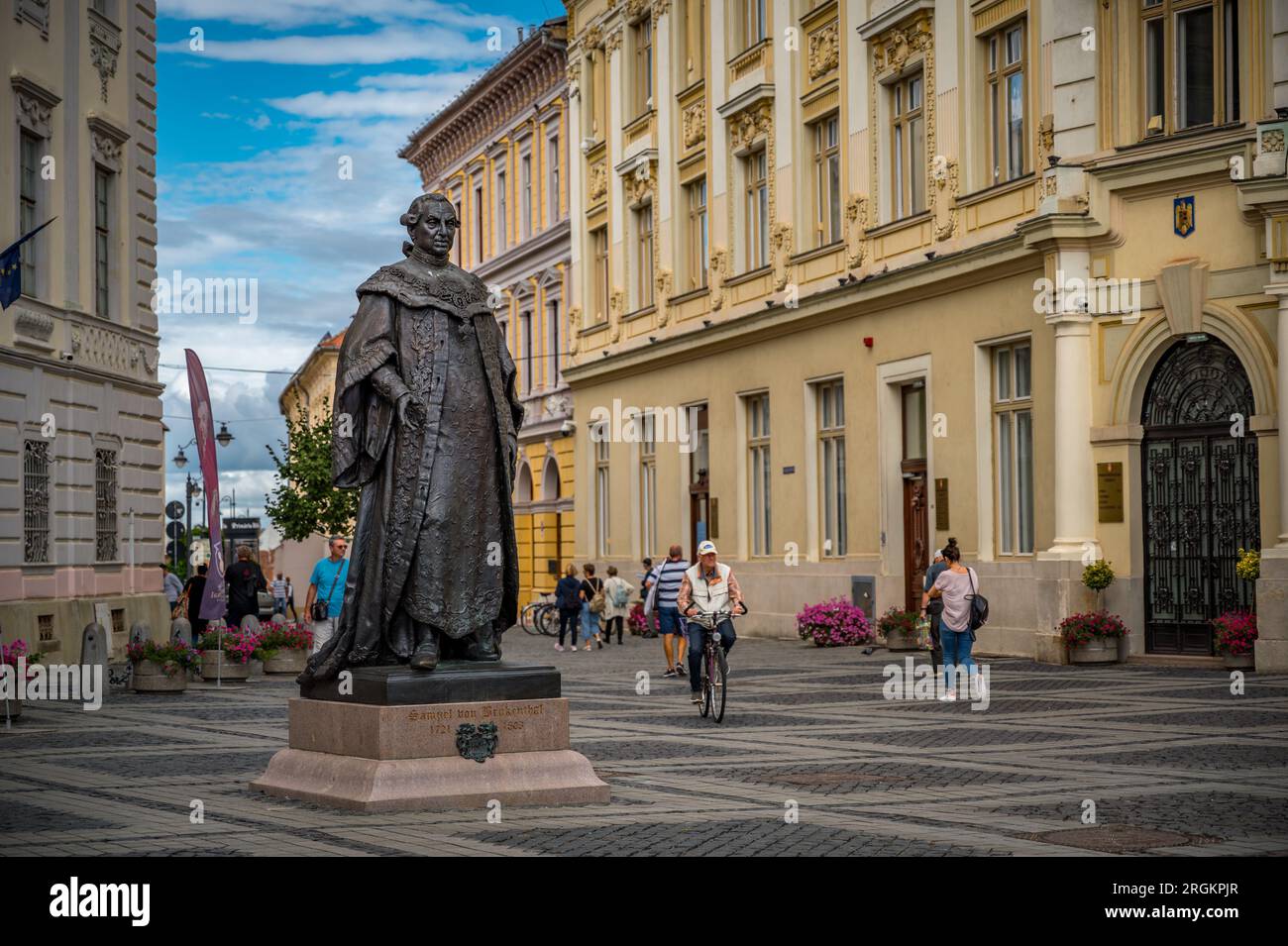 Sibiu, Rumänien - September 16 2022: Statue von Samuel von Brukenthal im historischen Zentrum von Sibiu. Leute, die im Hintergrund laufen Stockfoto