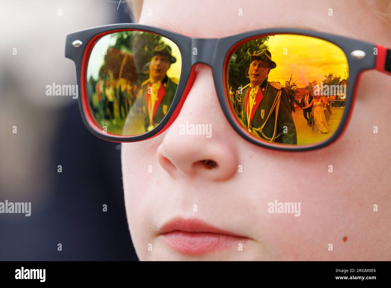 Vechta, Deutschland. 10. Aug. 2023. Ein Scharfschützenbruder spiegelt sich in der Sonnenbrille eines Jungen während der Prozession am Stoppelmarkt wider. Das traditionelle Festival findet seit 725 Jahren statt. Der Ehrengast bei der Eröffnung ist Lilo Wanders. Kredit: Friso Gentsch/dpa/Alamy Live News Stockfoto