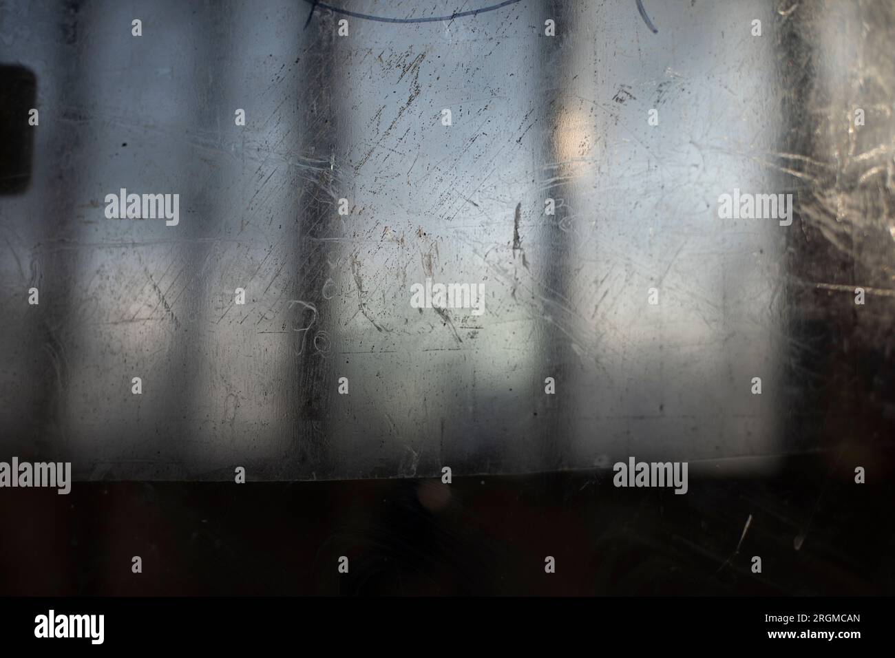 Zerkratzte Oberfläche. Kratzer auf Glas. Transparente Textur in kleinen Strichen. Unscharfer Hintergrund außerhalb des Fensters. Stockfoto