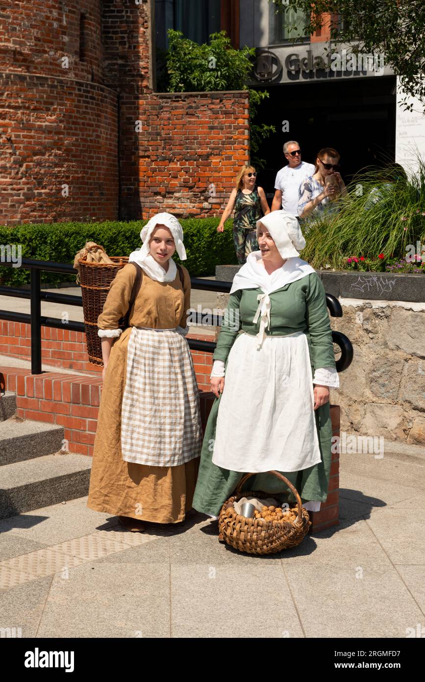 Weibliche Reenactors als mittelalterliche Straßenverkäufer, die auf dem Targ Rybny oder dem Fischmarkt in Danzig, Polen, Europa, EU Straßenschreie machen Stockfoto