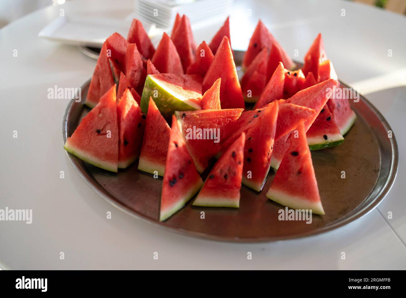Viele kleine dreieckige Scheiben reifer roter Wassermelone auf einem Teller. Isoliert auf weißem Hintergrund. Blick von oben Stockfoto