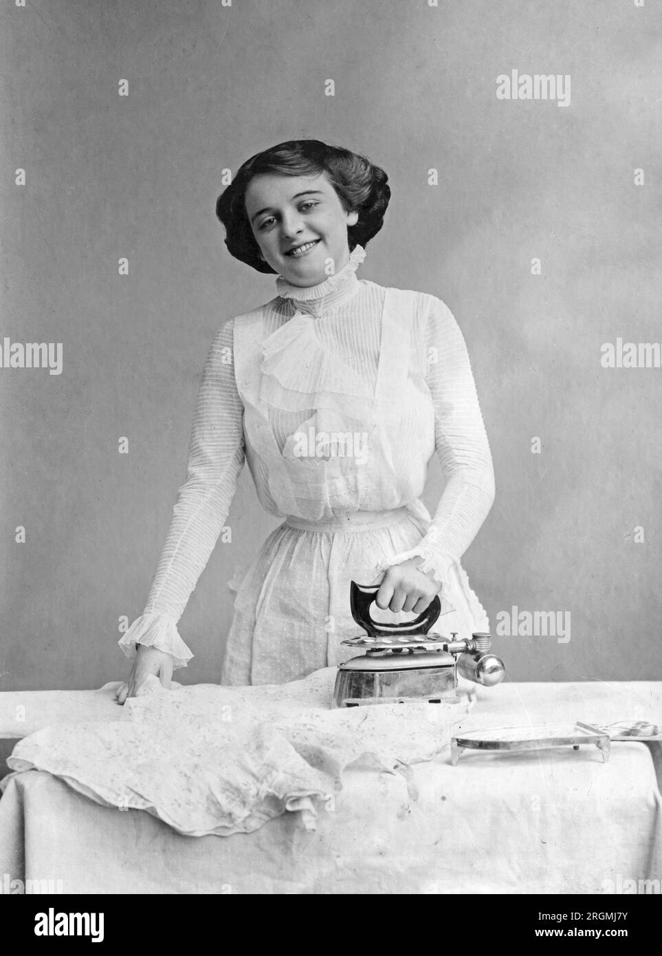 Frau, die ein Bügeleisen benutzt, ein Kleid bügelt ca. 1912-1930 Stockfoto
