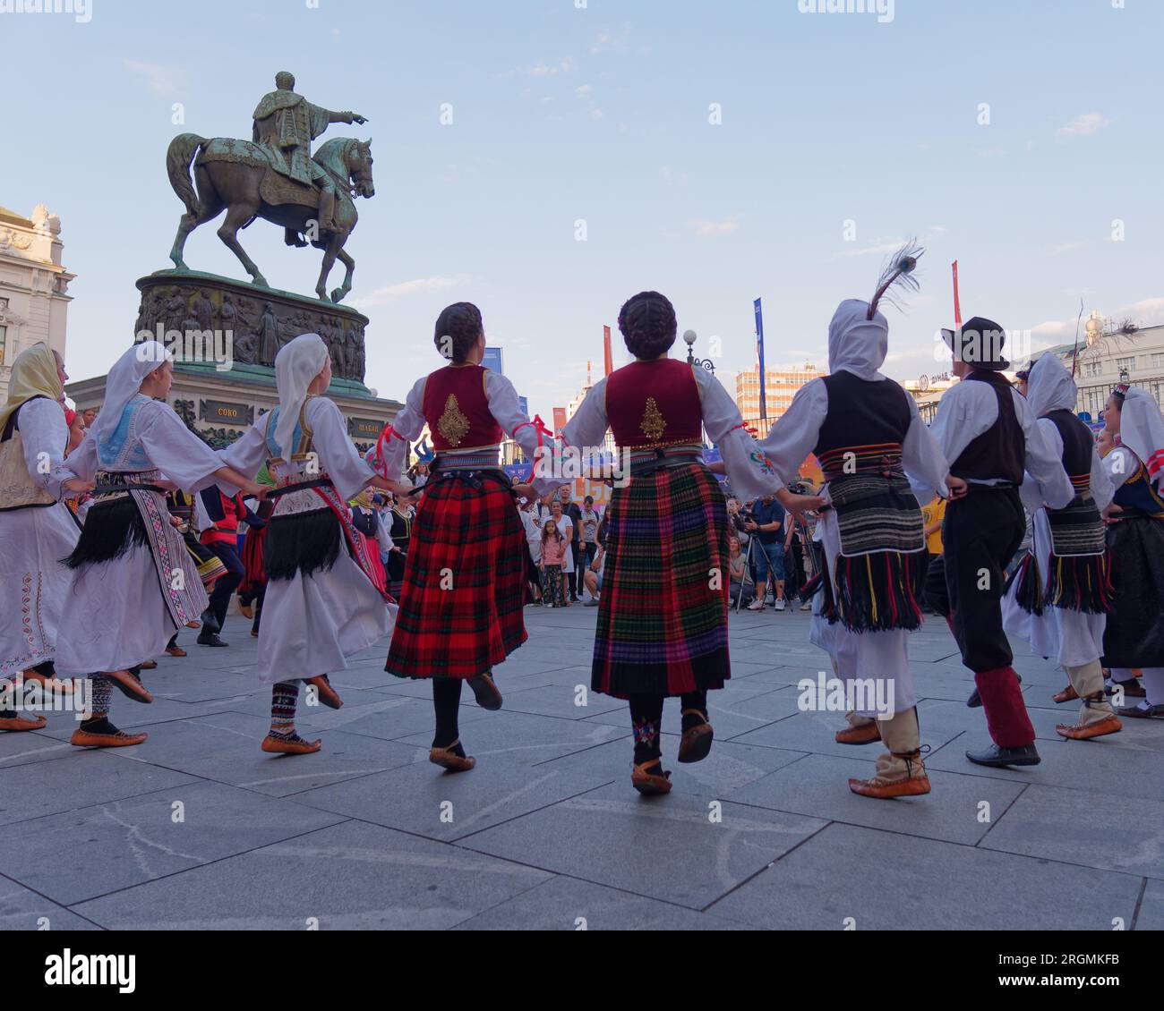 Platz der Republik mit Menschen in traditionellen Trachten, die vor dem Prinz-Mihailo-Denkmal in Belgrad, Serbien, tanzen, 10. August 2023. Stockfoto