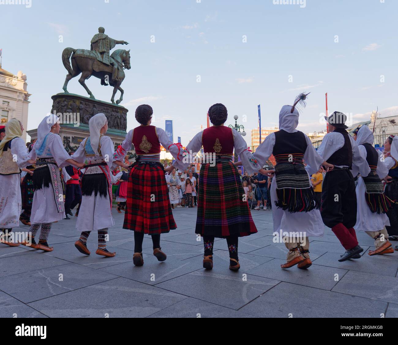 Platz der Republik mit Menschen in traditionellen Trachten, die vor dem Prinz-Mihailo-Denkmal in Belgrad, Serbien, tanzen, 10. August 2023. Stockfoto