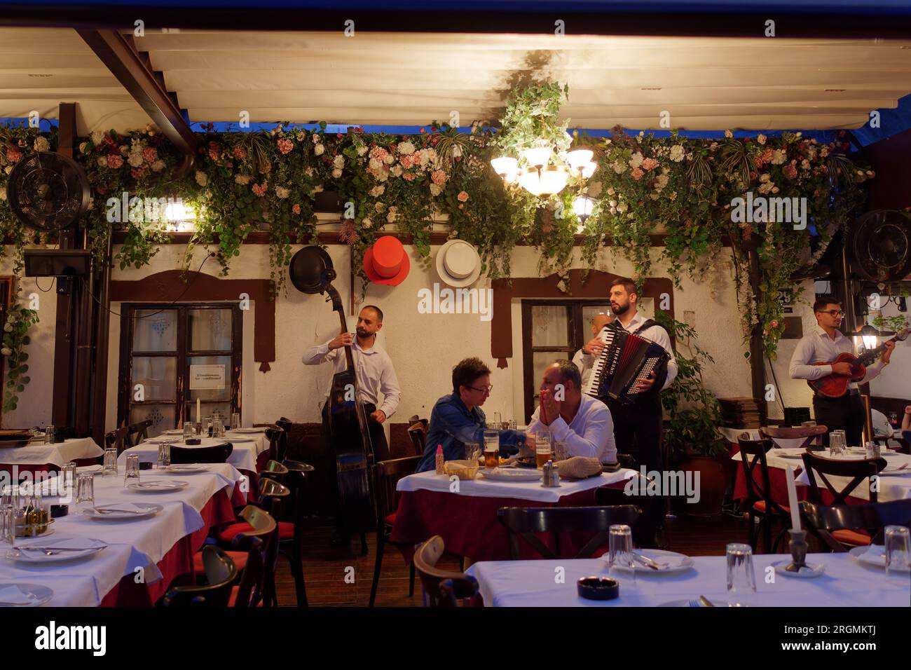 Musiker spielen an einem Sommerabend in Belgrad, Serbien, im berühmten Restaurant Three Hats vor den Gästen in der Skadarlija Straße. August 2023. Stockfoto
