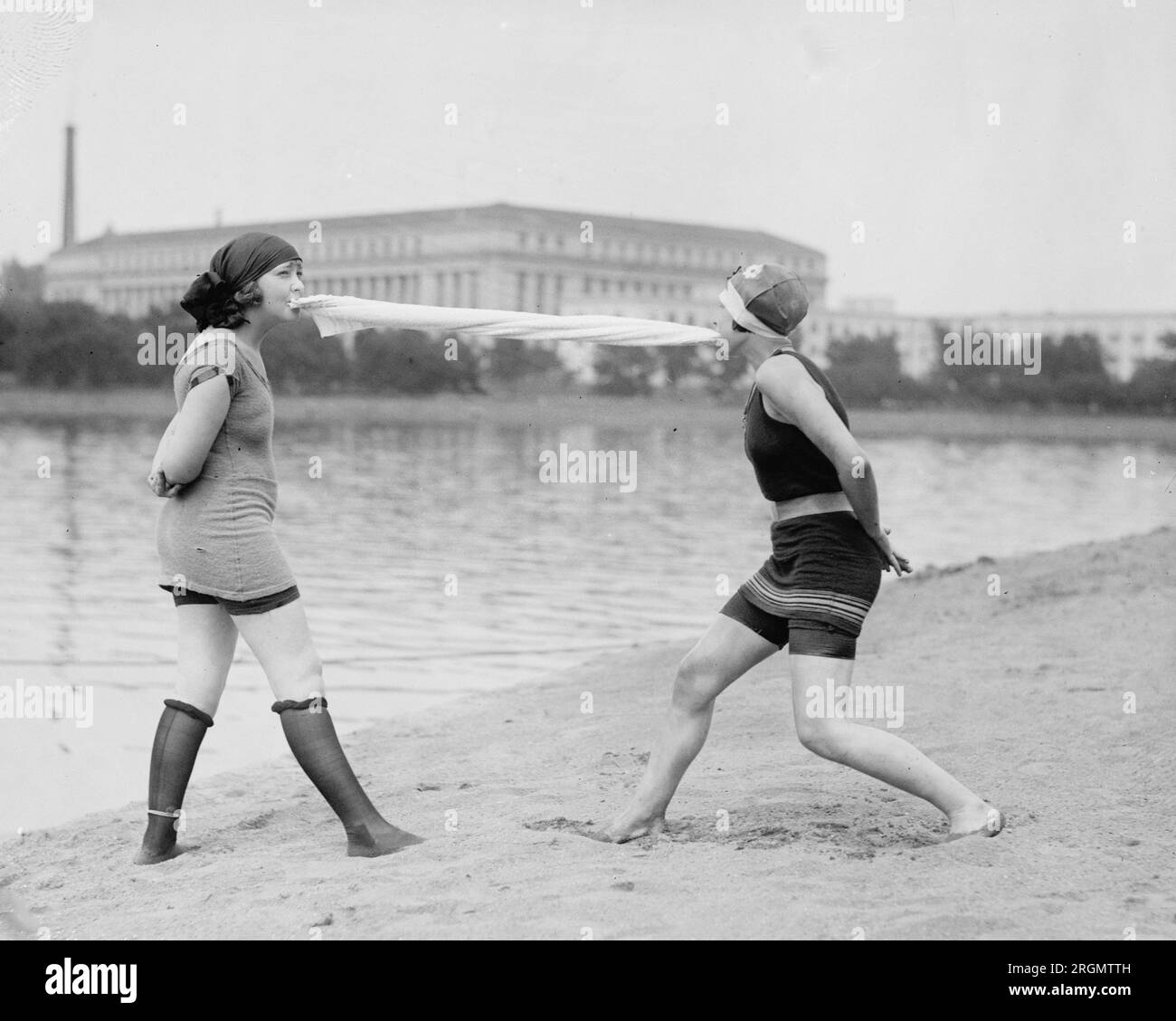 Zwei junge Frauen am Strand, die mit den Zähnen ein Tuch ziehen. 1922 Stockfoto