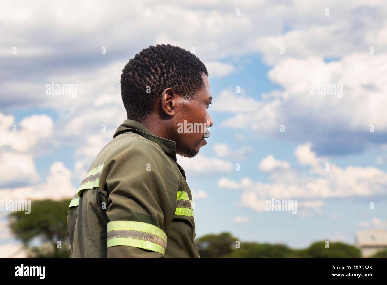 afrikanische Männer, gekleidet in Arbeitskleidung, laufen durch die Straßen der Stadt, hellblauer Himmel im Hintergrund Stockfoto