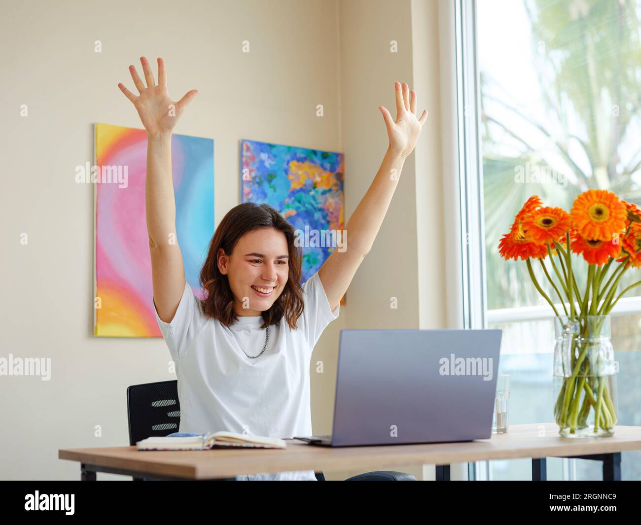 Lateinische junge Frau, die sich aufregt und Fäuste sammelt, feiert Karriereleiter-Beförderung oder -Belohnung, Studierende, die am Schreibtisch sitzen, erhalten Online-Nachrichten, großartige Ergebnisse, erfolgreiche Arbeit oder Studienkonzept Stockfoto