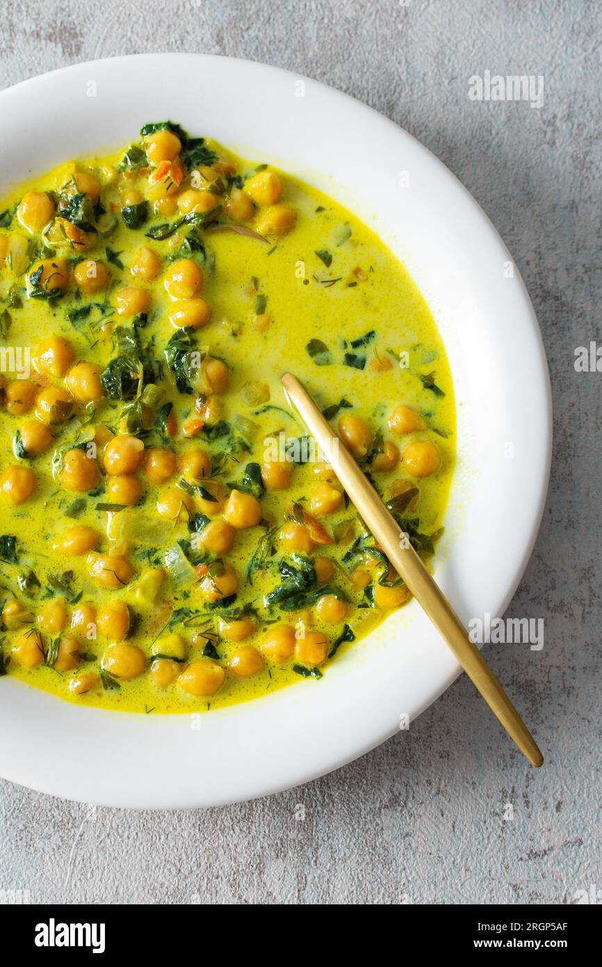 Gesundes, leckeres Mittagessen, Suppe mit Kichererbsen und Spinat, mit Gewürzen und frischen Kräutern, mit Kokosmilch, Draufsicht Stockfoto