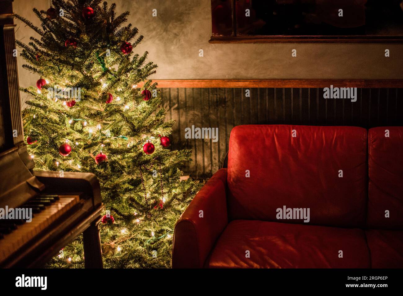 Gemütliche Wohnzimmerecke mit weihnachtsbaum und Klavier. Stockfoto