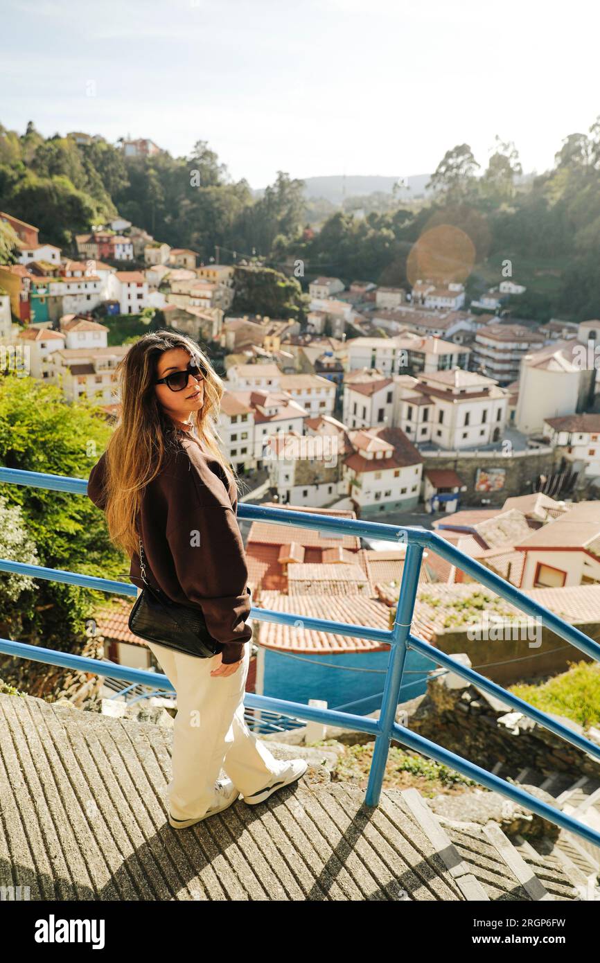 Ein Mädchen an einem Aussichtspunkt, wo man die Stadt Cudillero von oben sehen kann Stockfoto