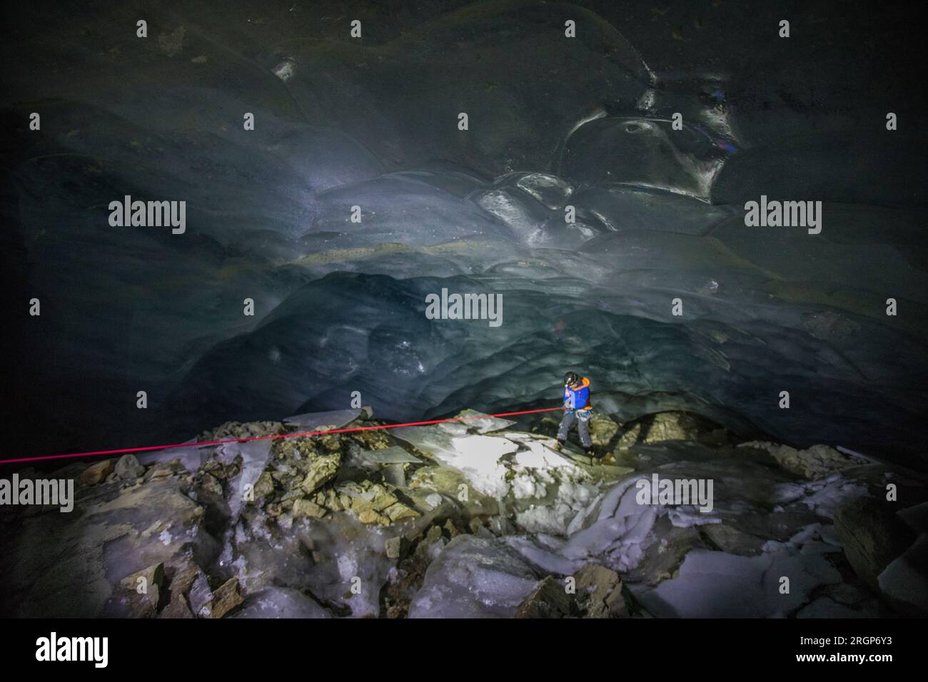 Ein Bergsteiger erkundet eine Höhle unter einem schmelzenden Gletscher Stockfoto