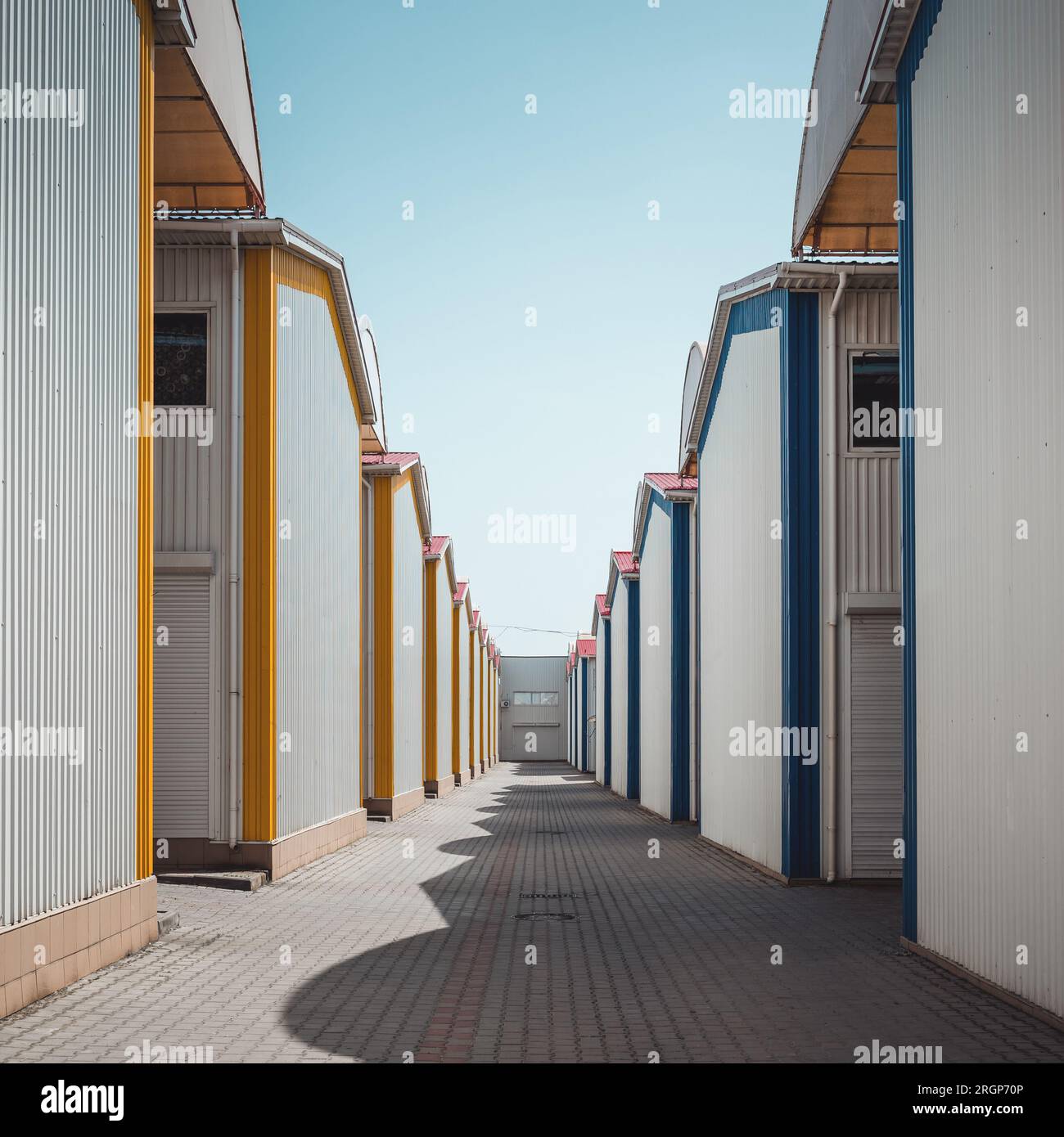 Reihen von Sommerhäusern aus Holz, bei denen es sich tatsächlich um Lagereinheiten in der Selbstlagereinrichtung handelt. Perspektive an einem sonnigen Tag. Stockfoto