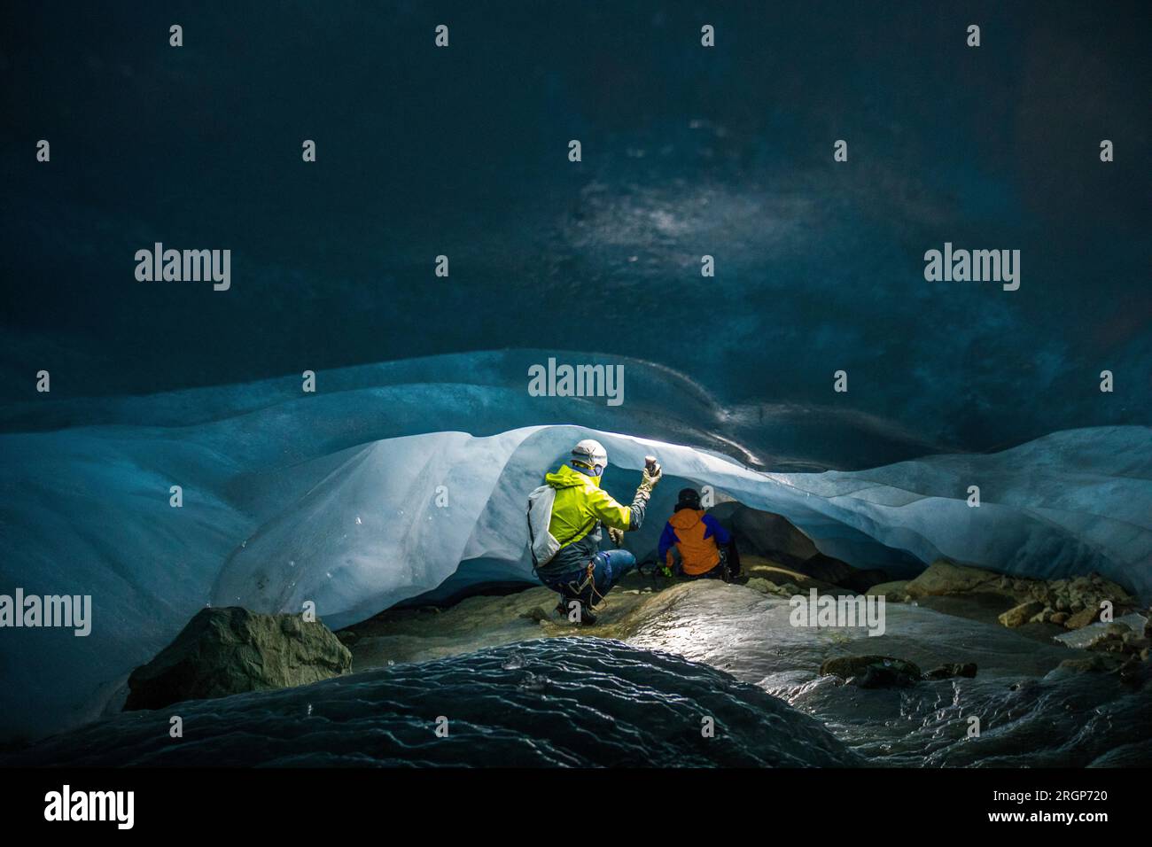 Rückansicht von zwei Entdeckern in einer niedrigen und engen Eishöhle Stockfoto
