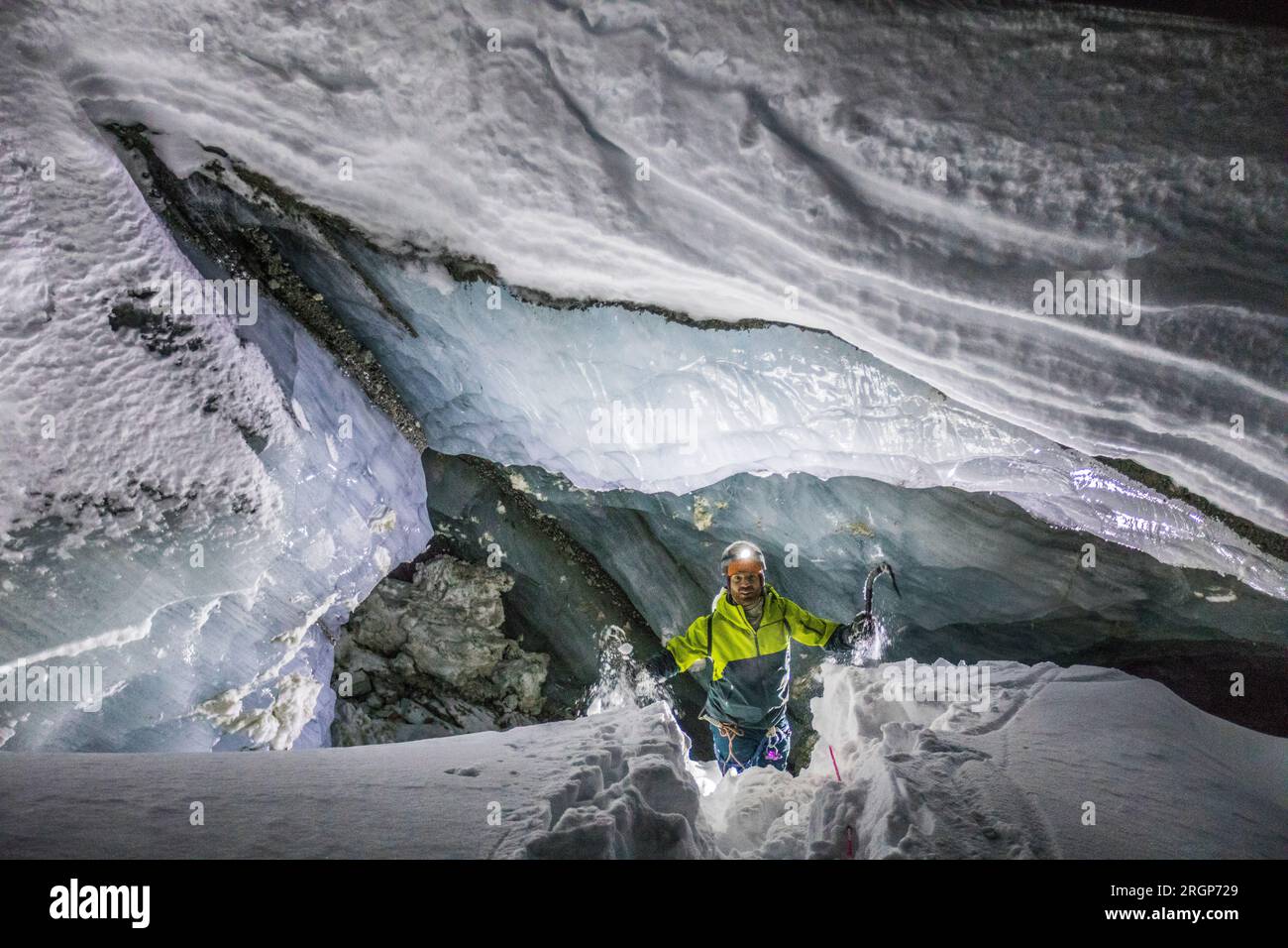 Explorer/Eiskletterer kommt aus dem Eingang der Gletschereishöhle Stockfoto