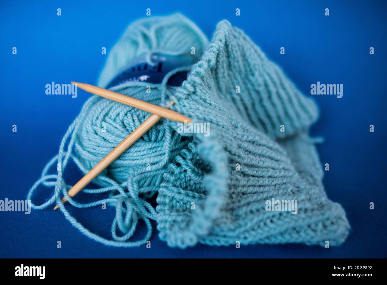 Blaues halbes Strickprojekt und Garn auf blauem Hintergrund Stockfoto