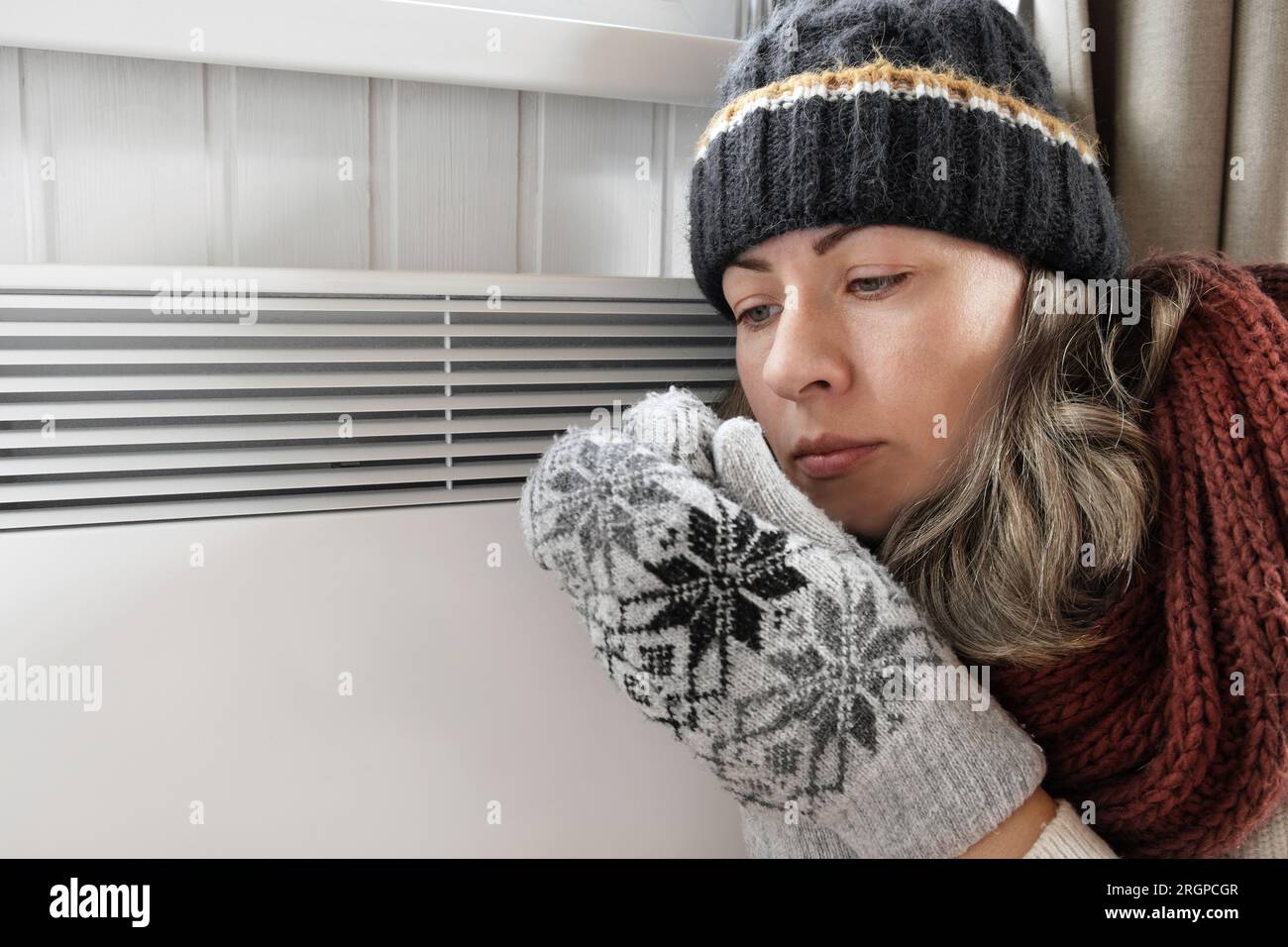 Junge gefrorene Frau, die einen Pullover trägt, schüttelt und friert bei Winterkälte mit Schockausdruck im Gesicht. Das Mädchen wärmt die Hände mit Atem über Elle auf Stockfoto