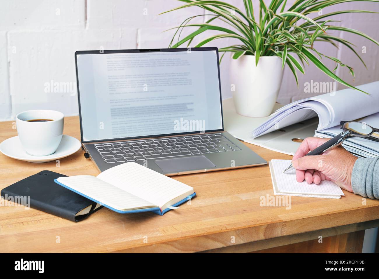 Handschriftliche Notizen auf einem Holzschreibtisch mit Laptop, Notizbüchern, Ordner und Kaffeetasse, Büroarbeitsplatz zu Hause, Kopierbereich, ausgewählter Fokus, eng Stockfoto