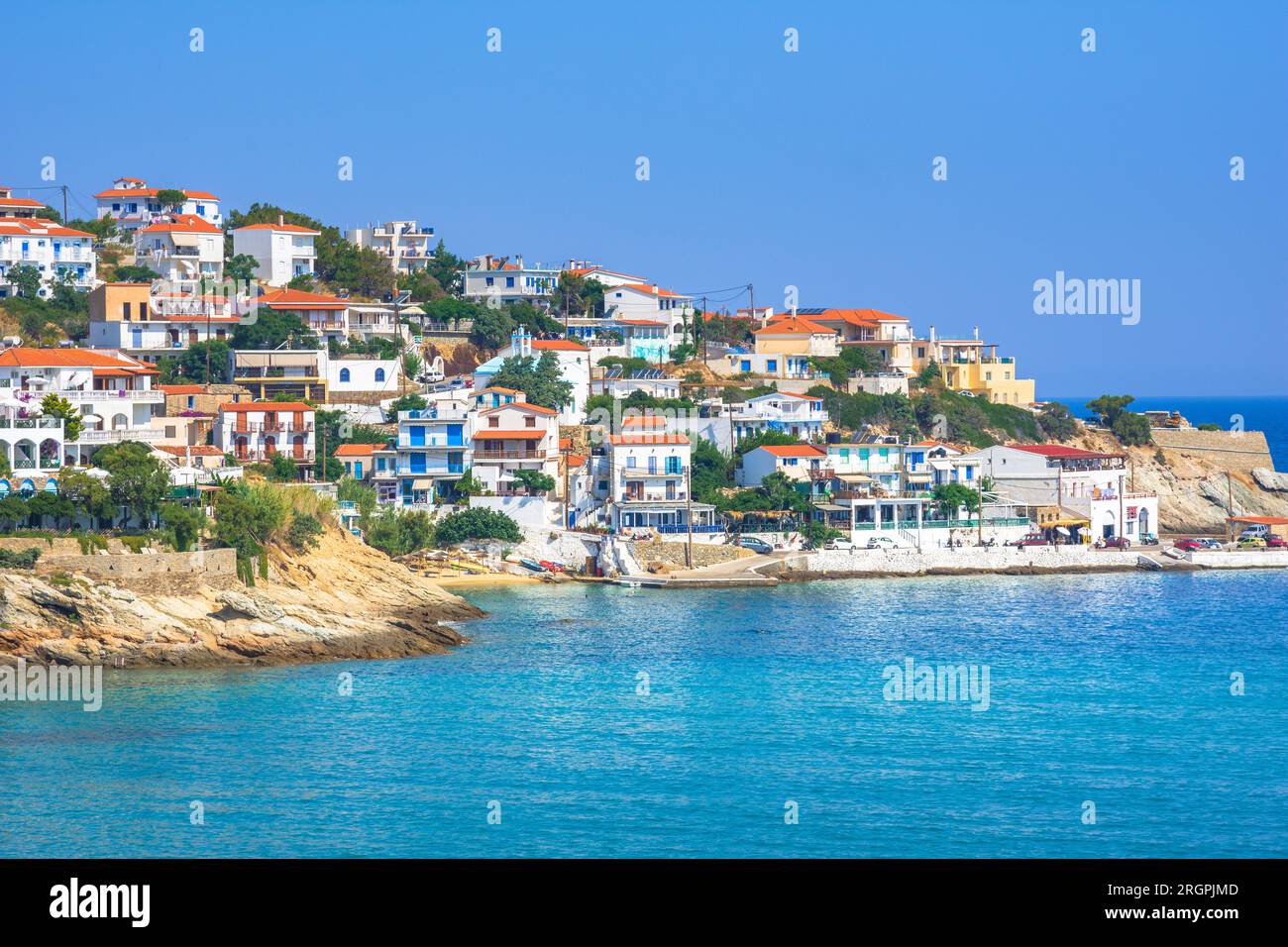 Schönes griechisches Fischerdorf Armenistis an einem ruhigen Sommermorgen. Hafen mit lokalem Strand in transparentem klarem Wasser in Ikaria, Griechenland Stockfoto