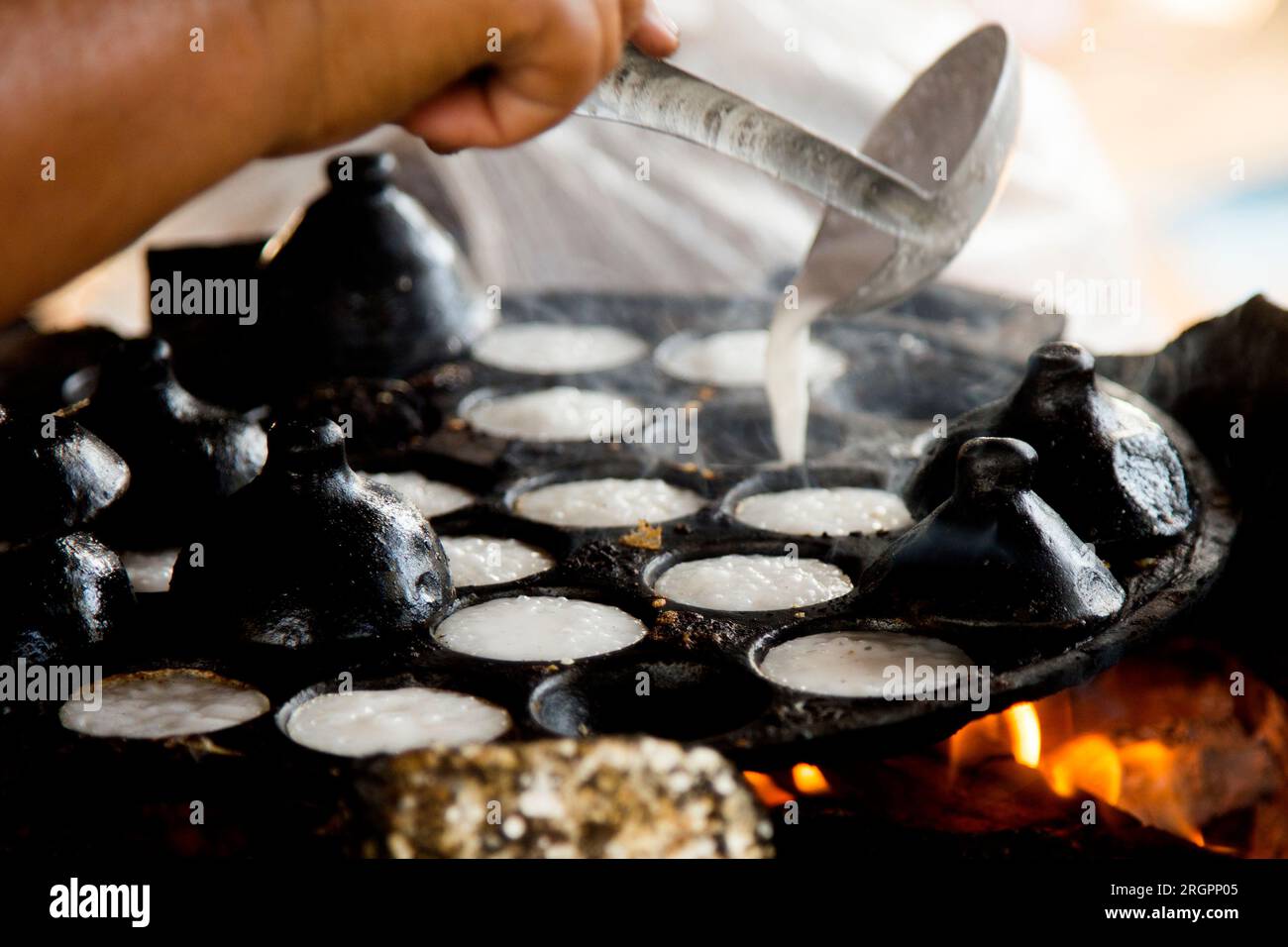 Frau bereitet Kokosnuss-thai-Desserts zu. Kanom krok ist ein leckeres thailändisches Mini-Pfannkuchen auf Kokosnussmilchbasis, das ebenfalls beliebt ist. Stockfoto