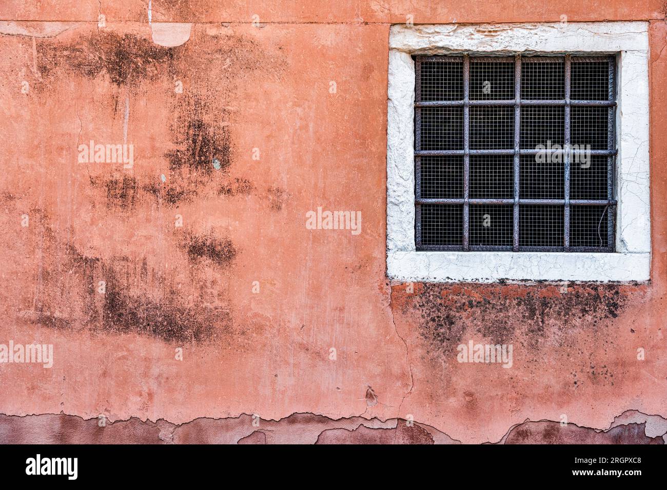 Alte rote Backsteinwand mit zwei rostigen Grillfenstern. Stockfoto