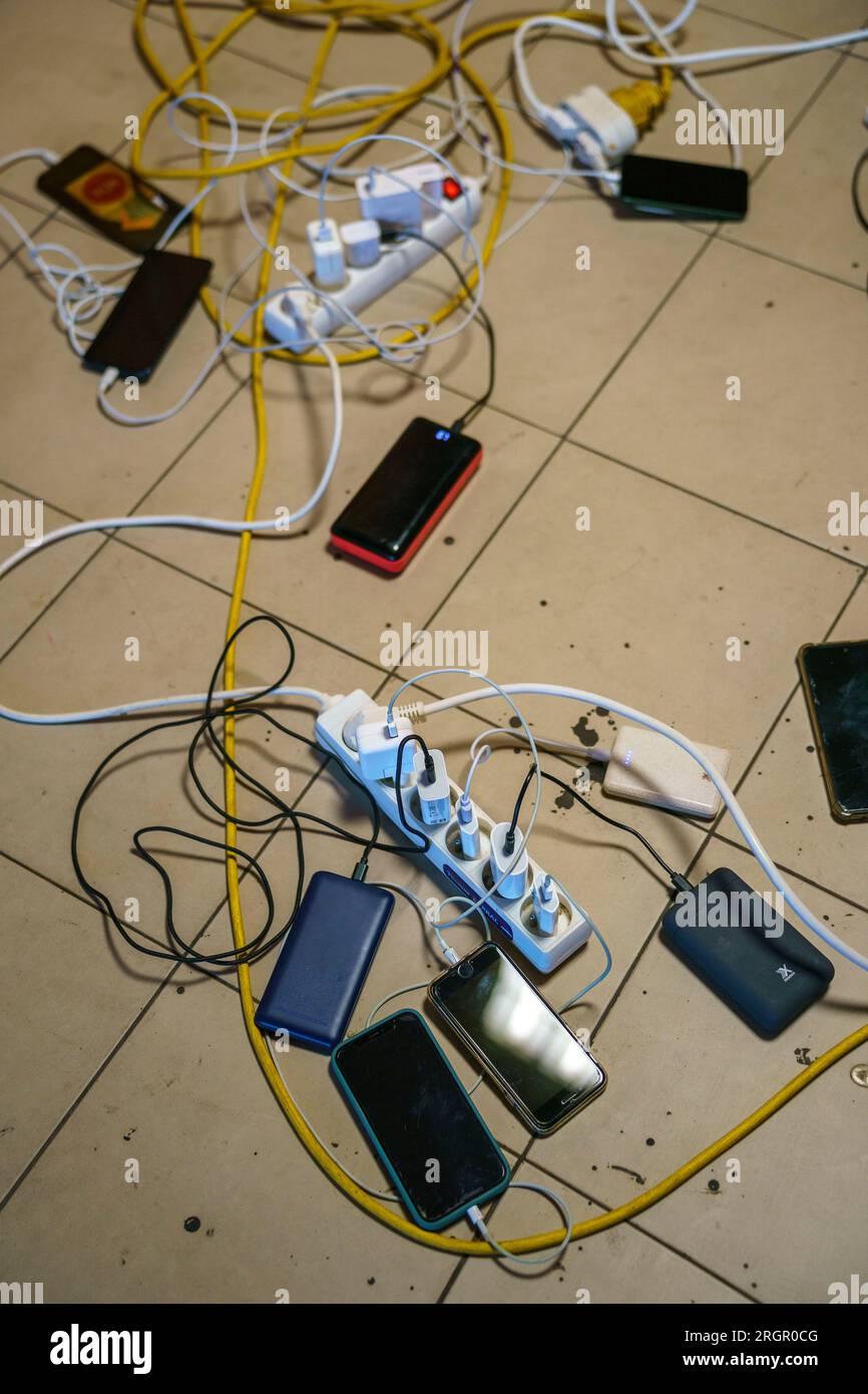 Der Boden ist voller durcheinander gerissener Steckdosenleisten, Netzkabel, Kabel und Ladetelefone Stockfoto