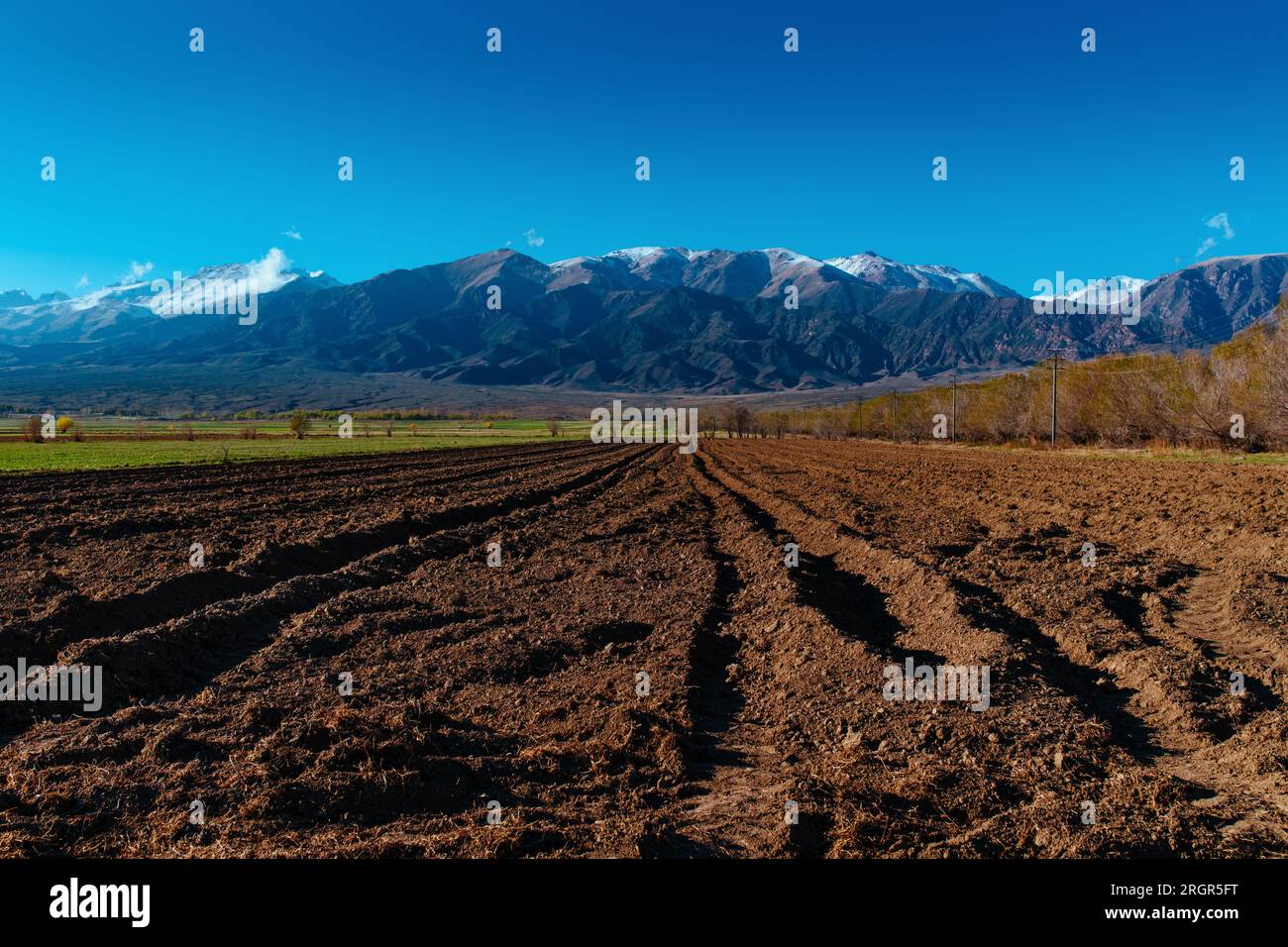 Frühlingslandschaft mit gepflügtem Feld auf Berghintergrund, Kirgisistan Stockfoto