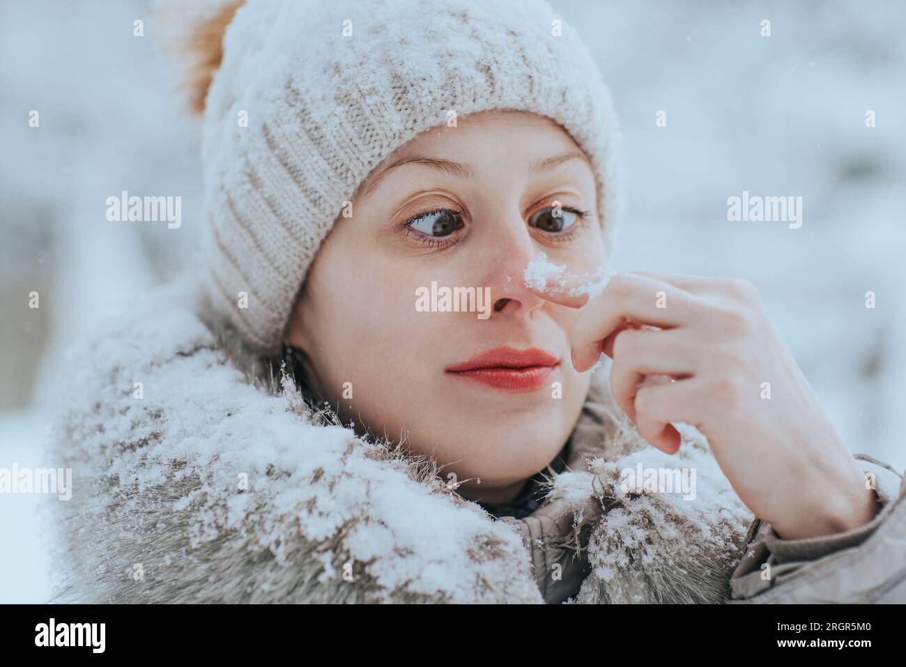 Porträt einer lustigen Frau in warmer Winterkleidung mit Schnee Stockfoto
