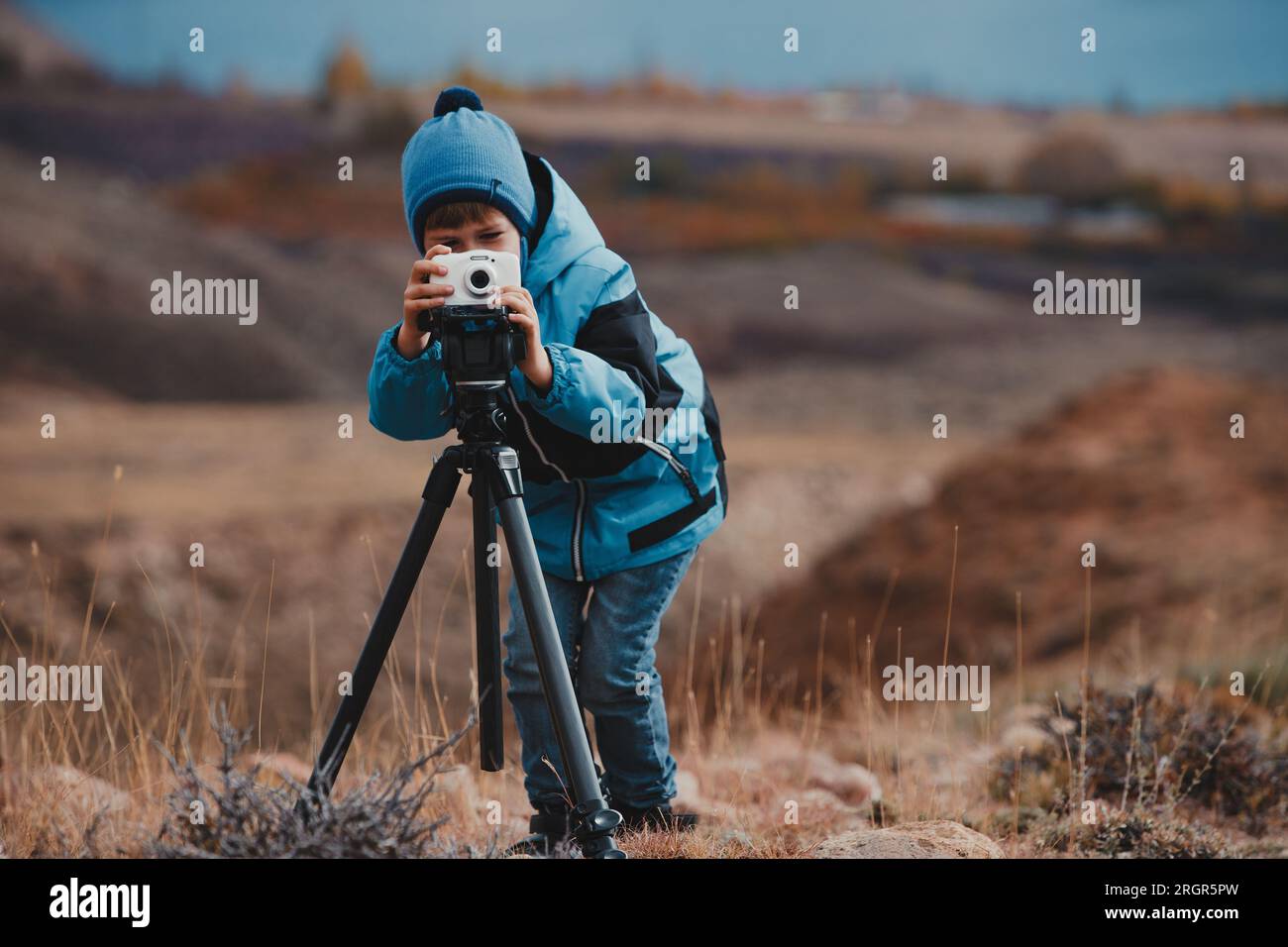 Ein Junge, der Fotos mit der Kamera auf einem Stativ in den Bergen macht Stockfoto